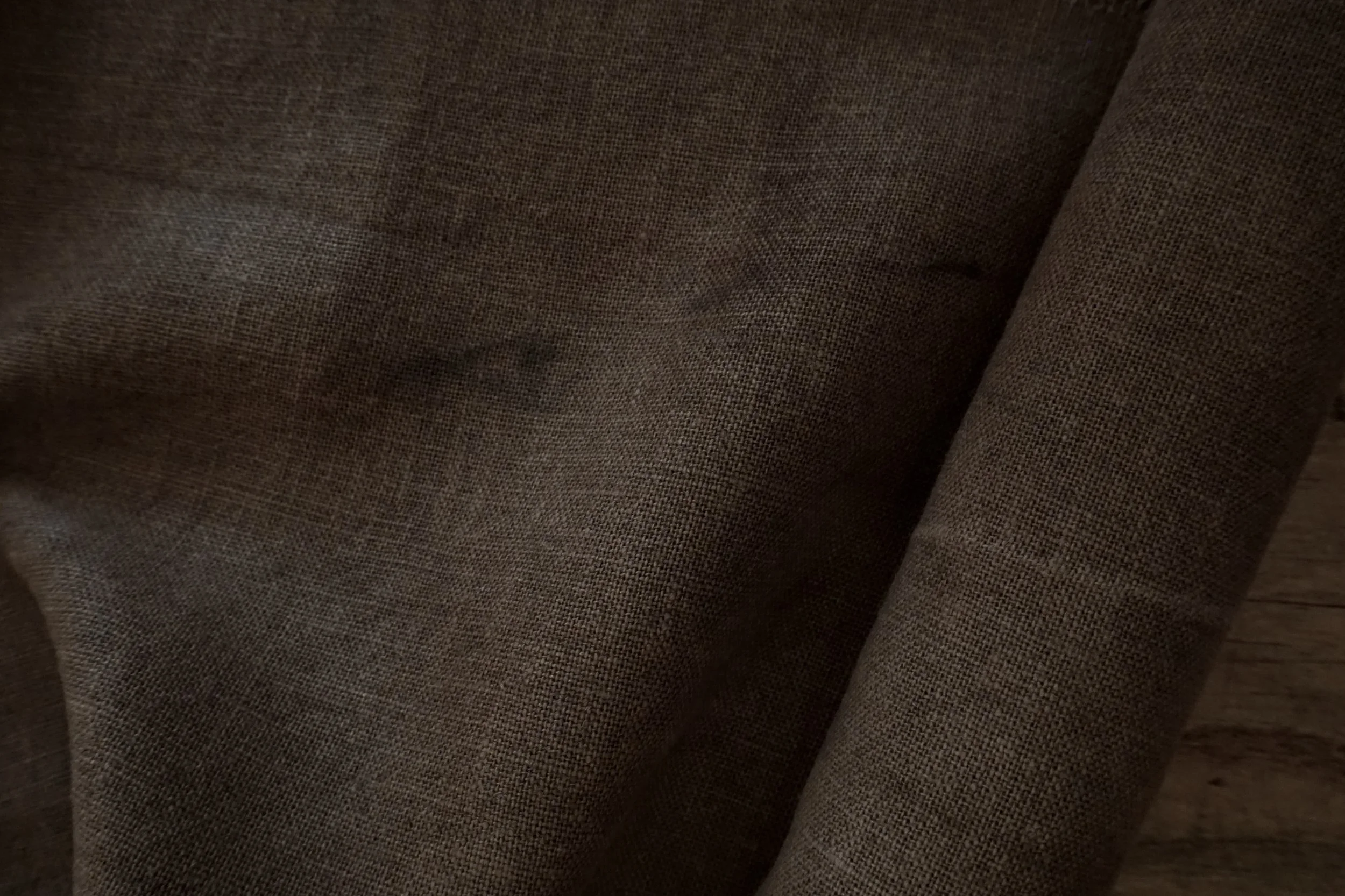 Tissu en lin ou en coton de couleur marron avec quelques taches et déchirures.