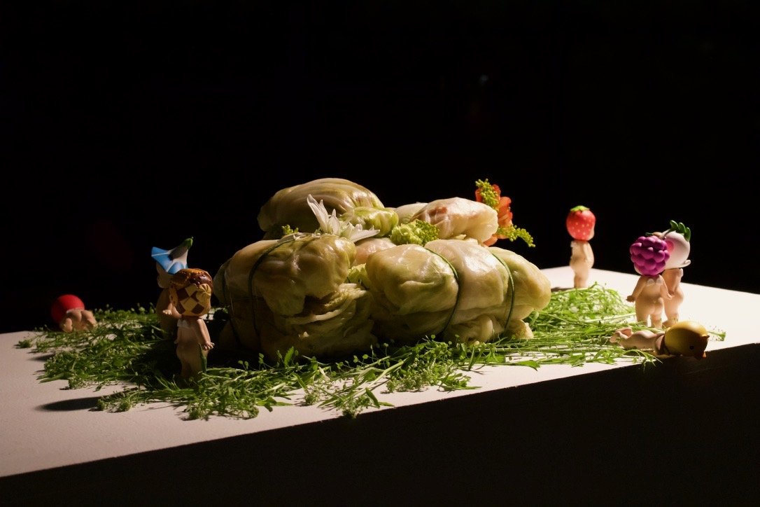 記憶 (kioku), 2023. Boiled cabbage, yellow cake, flowers, cucumber skin, plastic dolls, music box audio
