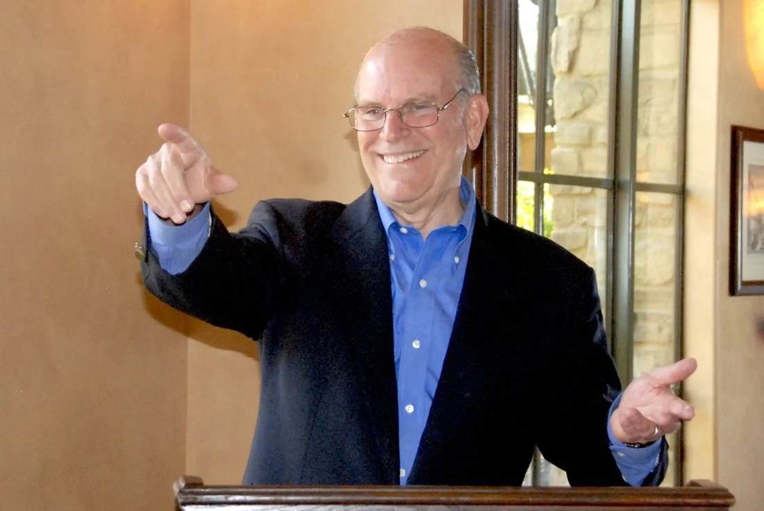 Craig speaking at a podium in a dark jacket