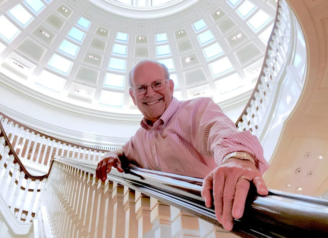 Craig in a pink shirt leaning on a railing under a domed ceiling