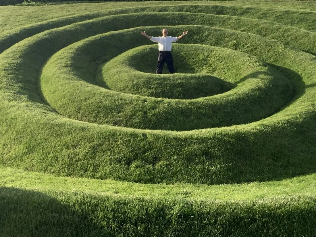 Craig standing with arms open in the middle of a giant green spiral lawn