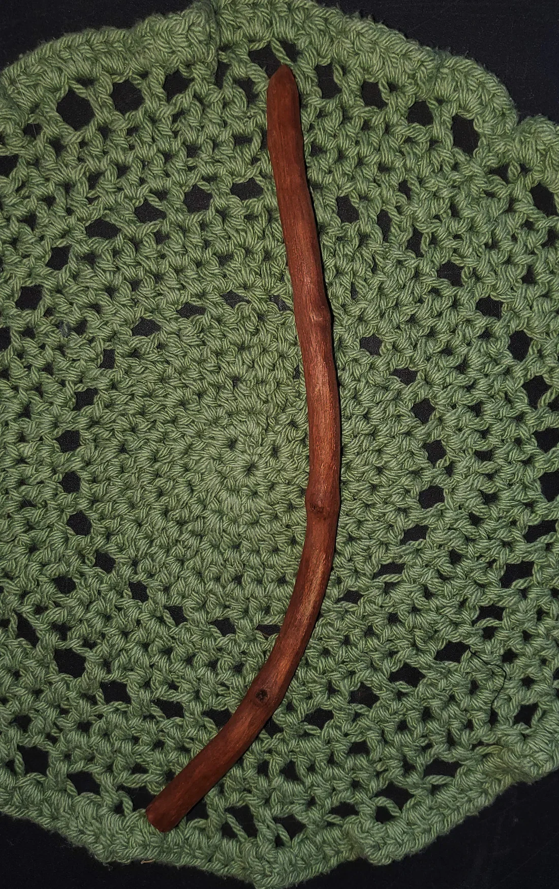 Wildwood Holler Wand #20, a curved Appalachian foraged wood ritual wand with warm natural coloring resting on a green crocheted mat.