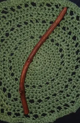 Wildwood Holler Wand #20, a curved Appalachian foraged wood ritual wand with warm natural coloring resting on a green crocheted mat.