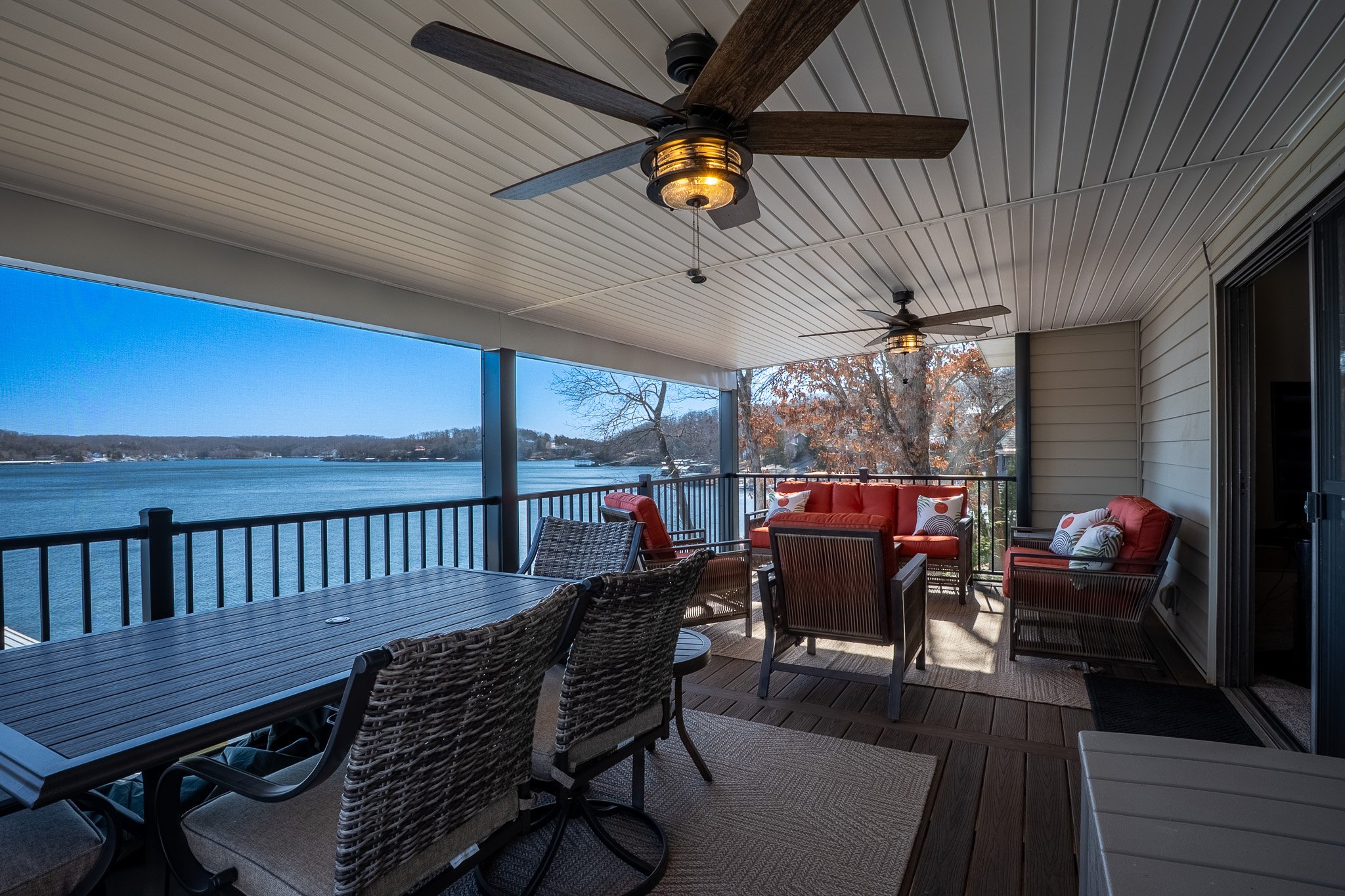 Covered porch with outdoor furniture, ceiling fans, and a view of a lake.