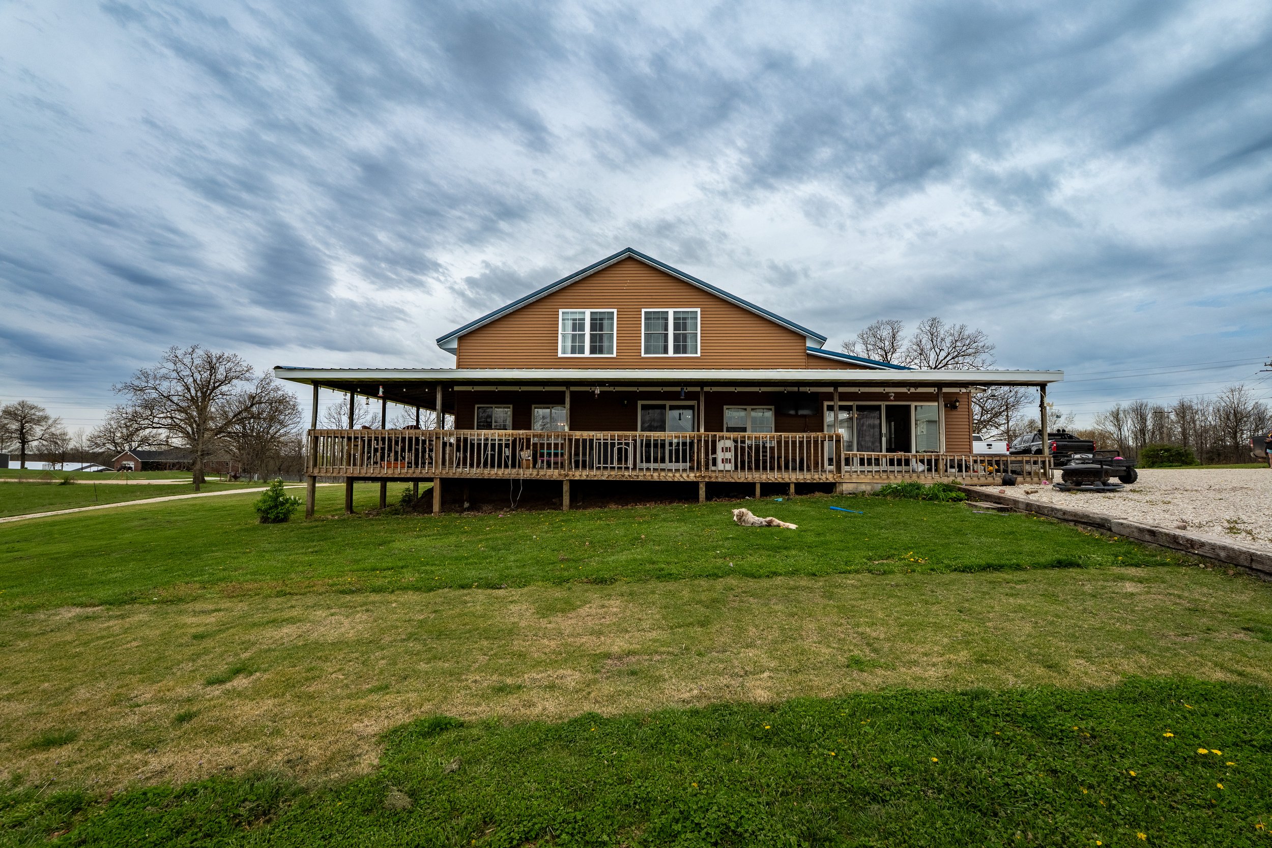 Large countryside house with a wooden porch and overcast sky
