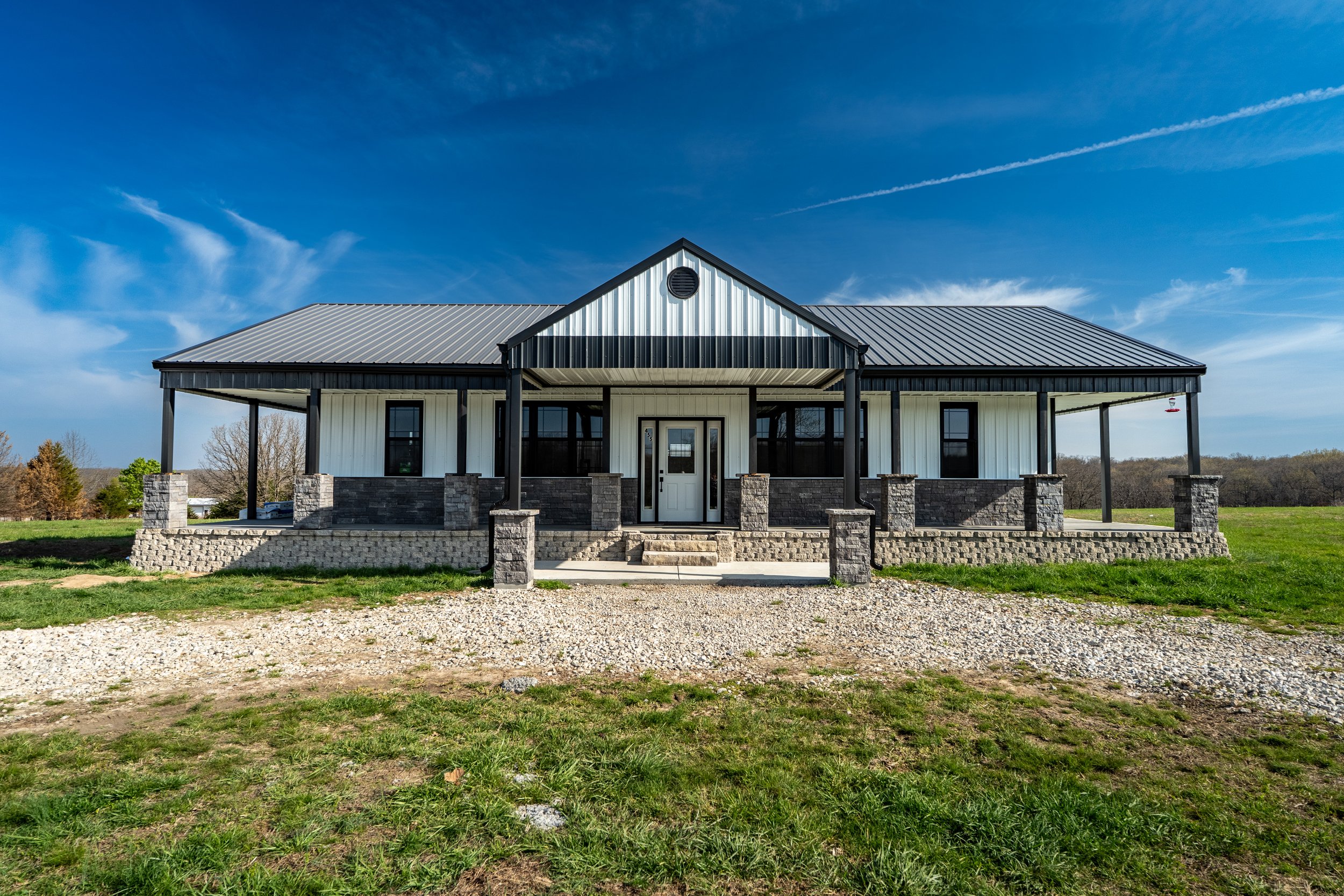 Modern farmhouse with metal roof and stone accents in rural setting