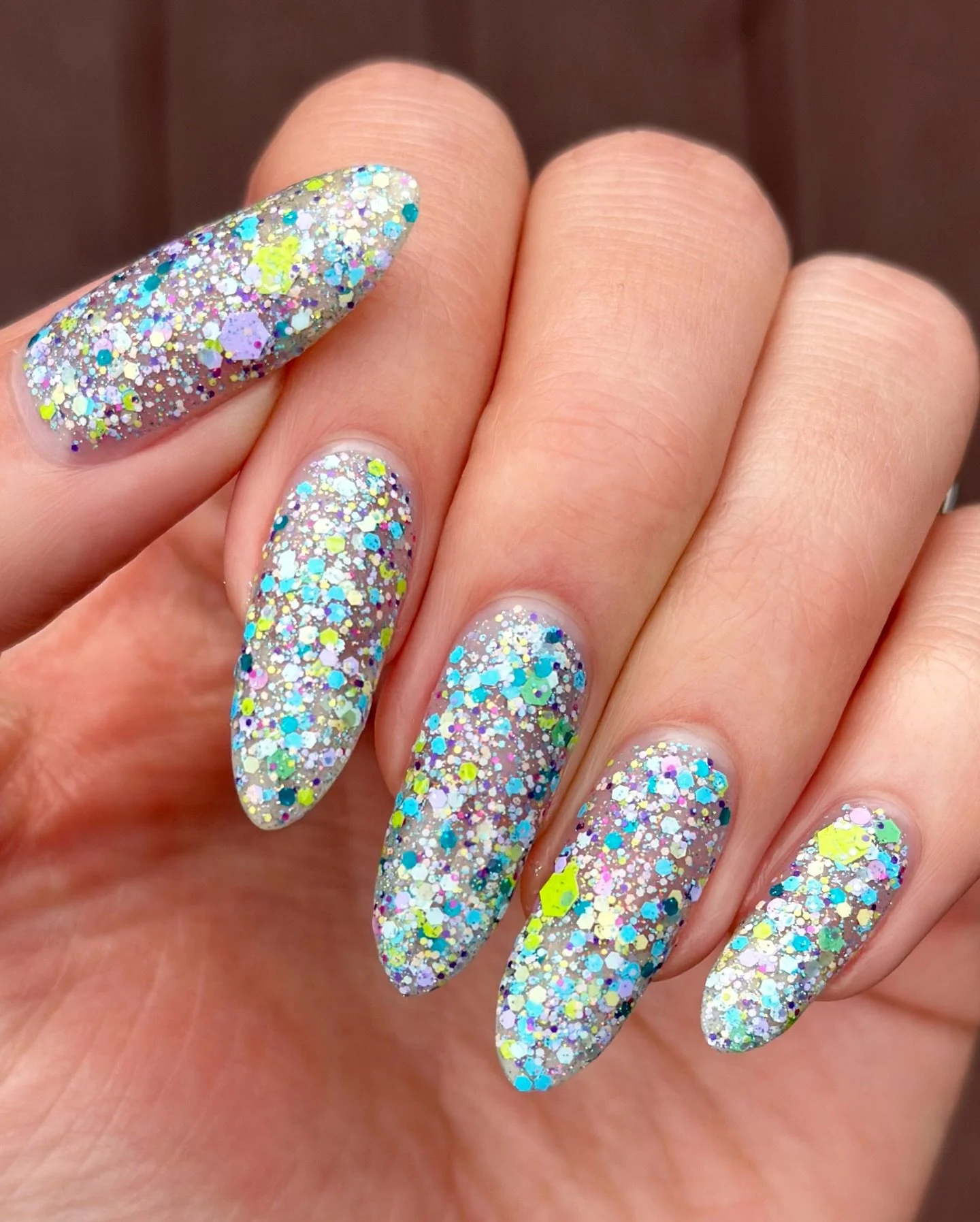 POINTILLISM 

A clear base filled with a variety of aqua, blue, purple, pink, green matte glitters in various sizes, orange/gold/green reflective glitter, and dainty holo.

Shown on its own and on top of Lotus Petals.

Can be worn solo in 2-3 coats o