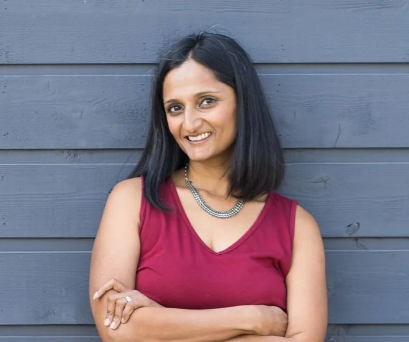 Indian woman, red tank top, silver necklace, with arms crossed and shoulder length black hair
