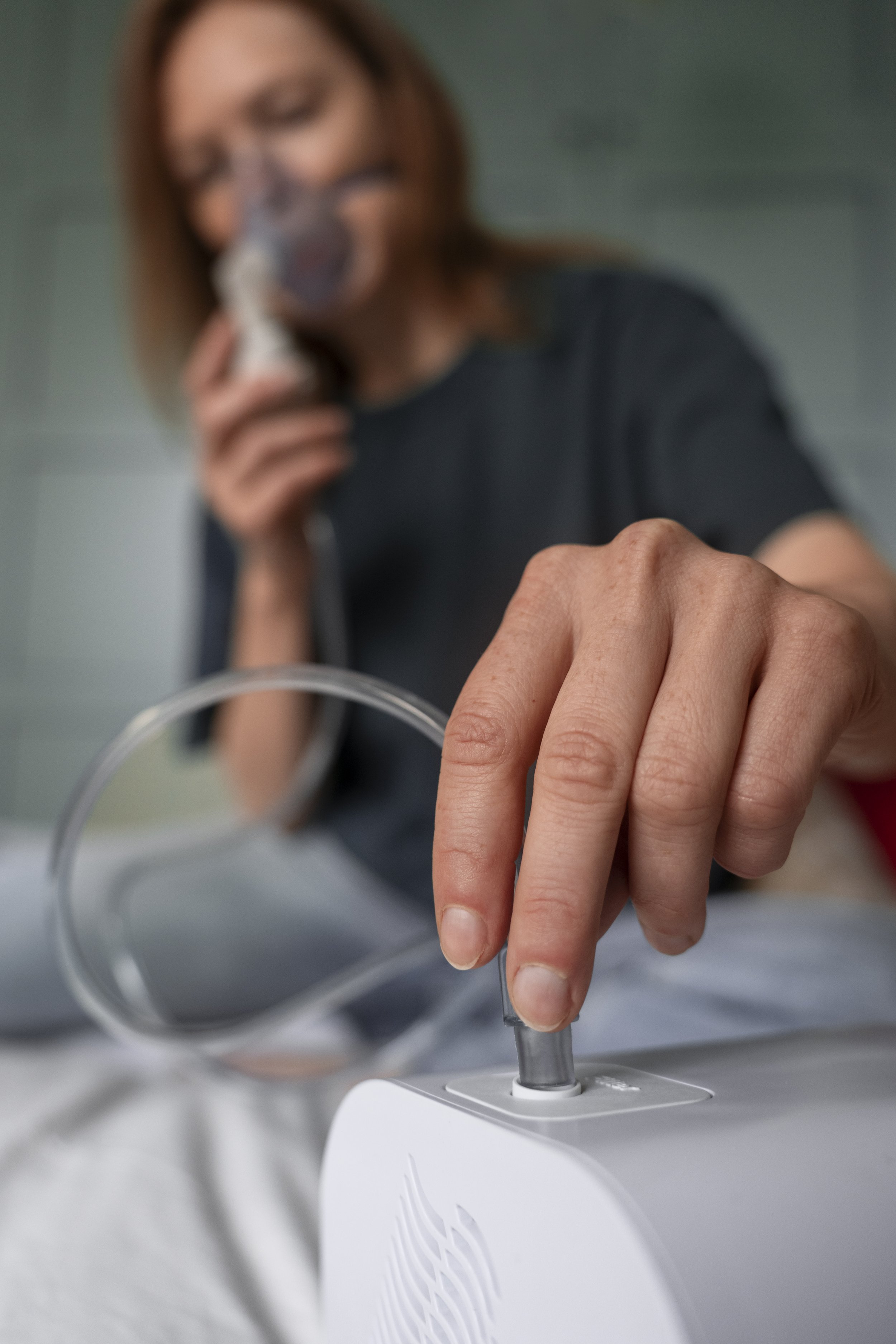 Close-up of a woman adjusting an oxygen tube at an oxygen bar, with her face blurred in the background.