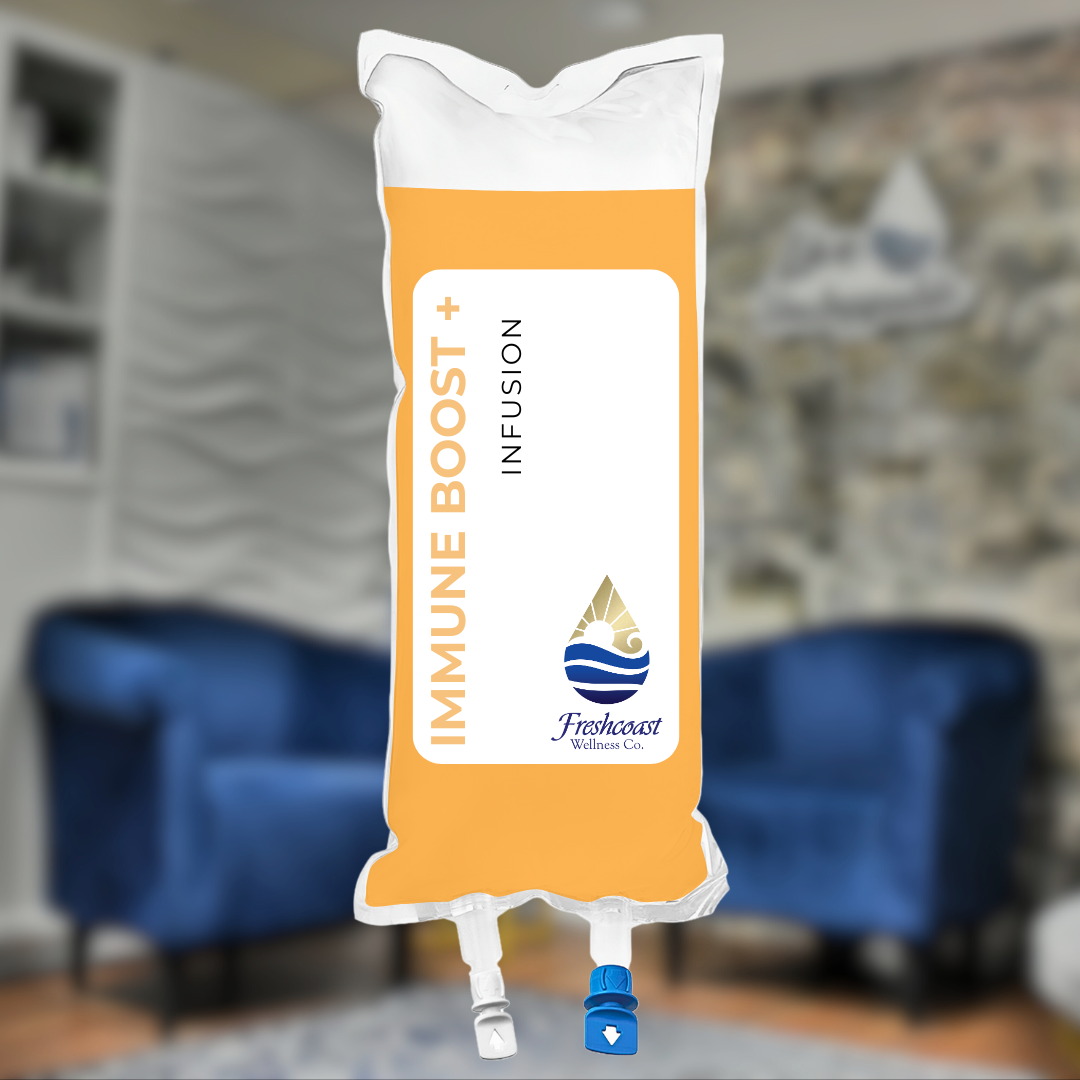 An IV infusion bag labeled "Immune Boost+" with the brand "Freshcoast Wellness Co." hanging in a room with a stone wall and blurred furniture in the background.