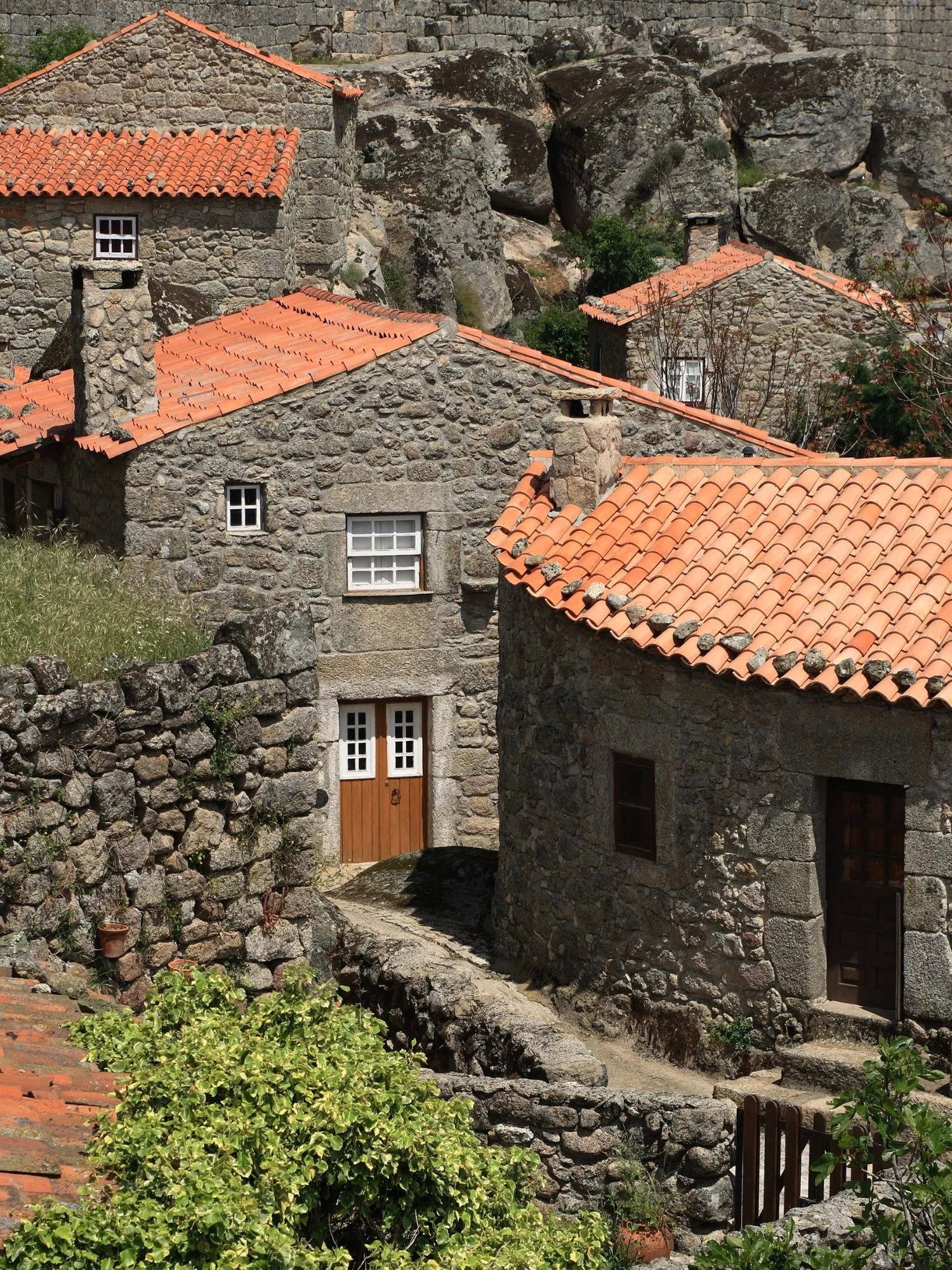 Stone houses with traditional terracotta roofs inside the medieval village of Sortelha, surrounded by granite walls and rocky outcrops, showcasing one of Portugal’s best-preserved historic villages.