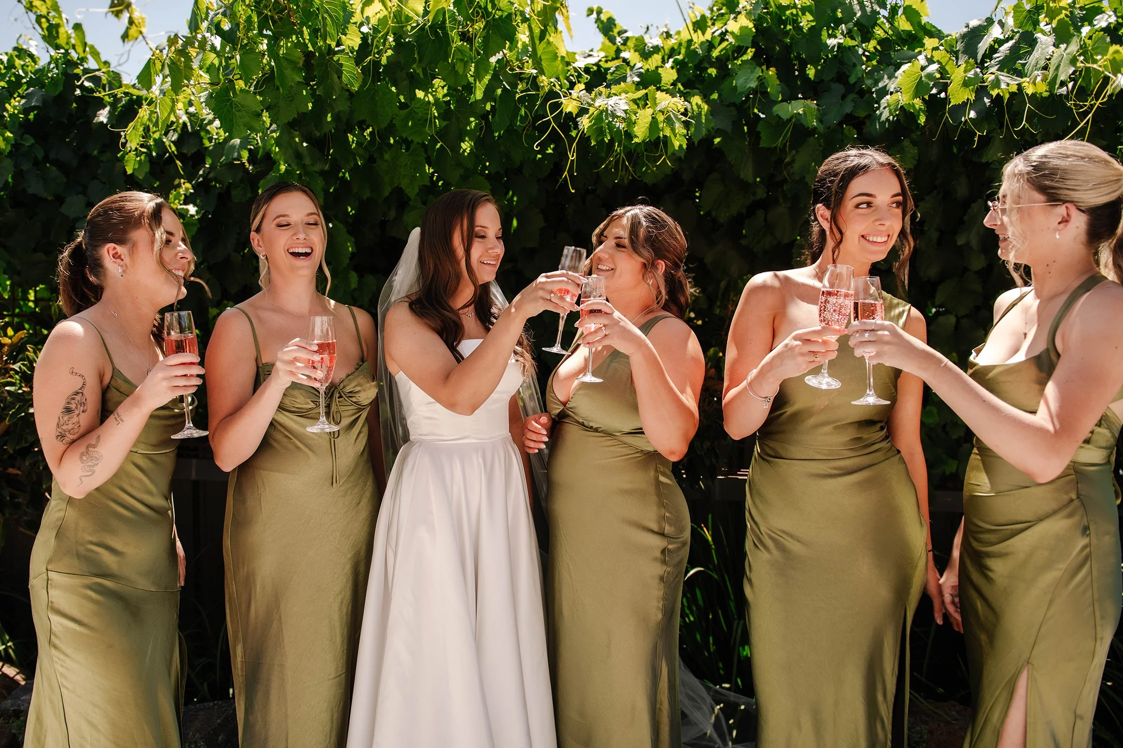 Bridesmaids laugh and cheer in posed candid shot in Ballarat with vines
