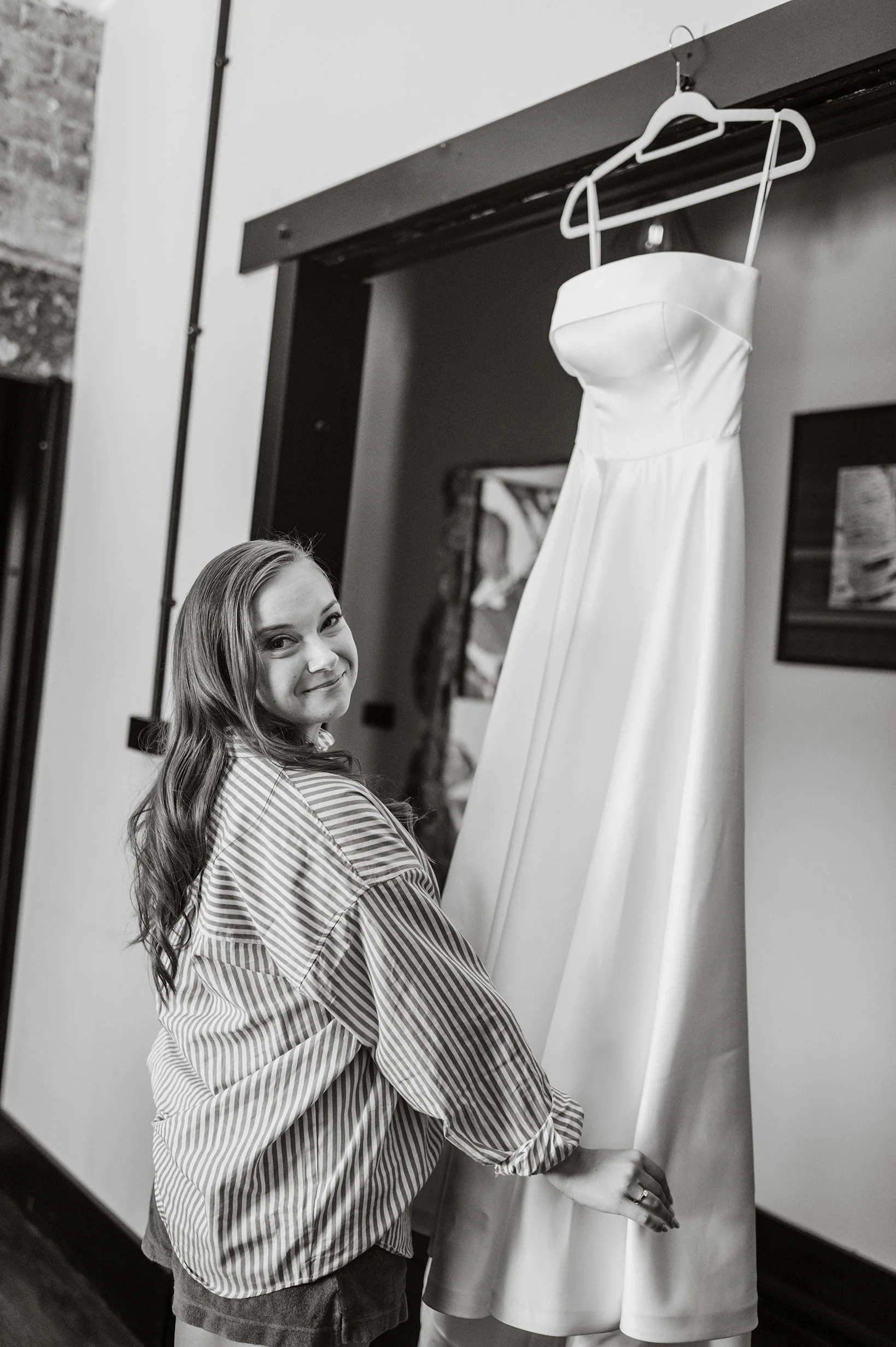 Bride looks back at the camera and smiles while she lifts the bottom of her wedding dress up