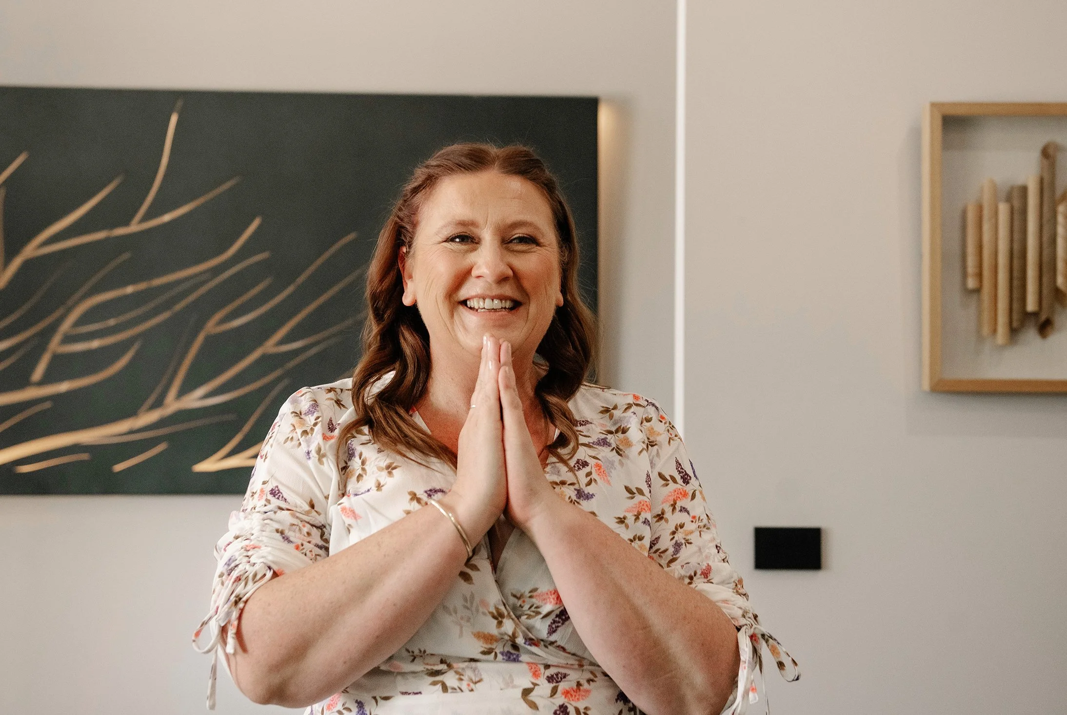 Mother of the bride smiles joyfully with her hands clasped together under her chin