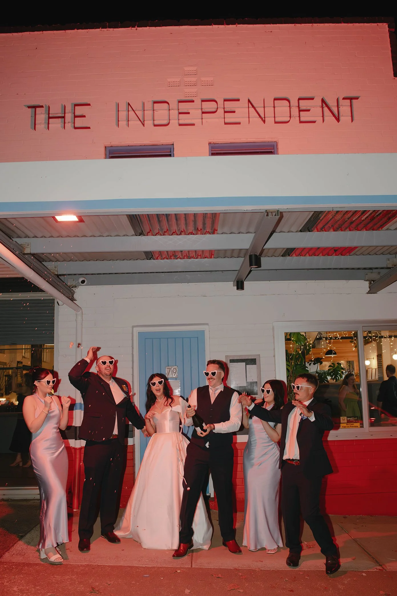 Wedding party dancing outside The Independent Gembrook wearing heart-shaped sunglasses at night after a Dandenong Ranges wedding reception