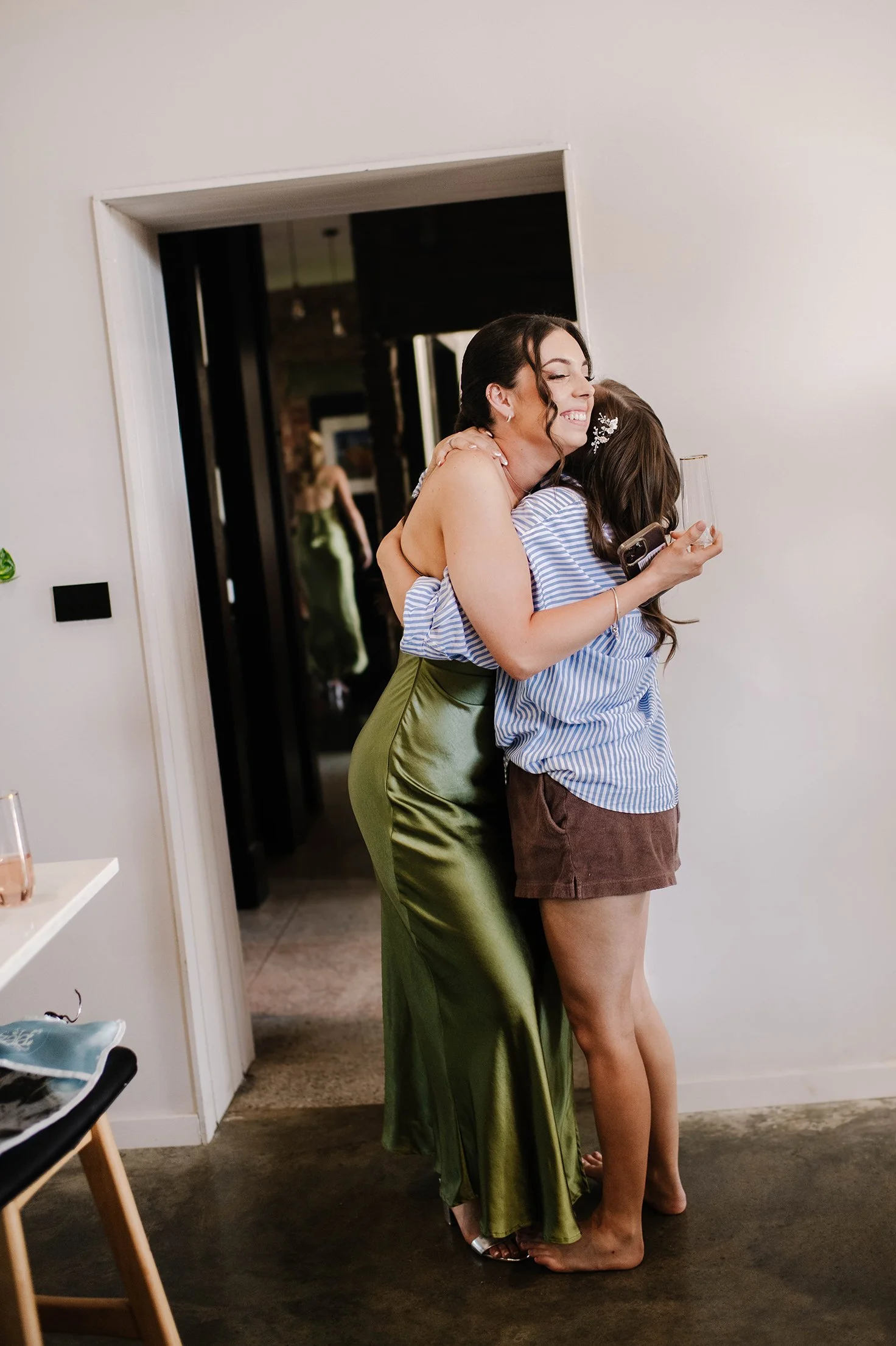 Bridesmaid hugs bride warmly at her first look to bride