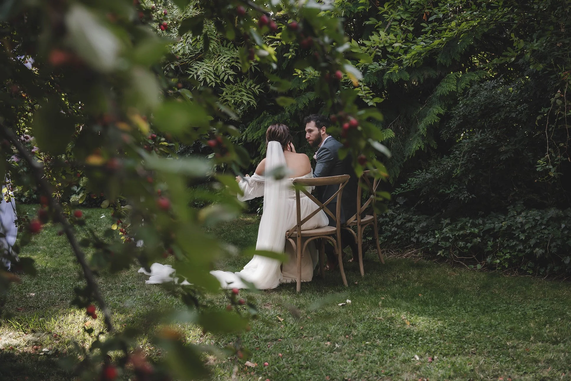 faded distance shot of bride and groom sitting at a table eating together in Chateau Dore garden