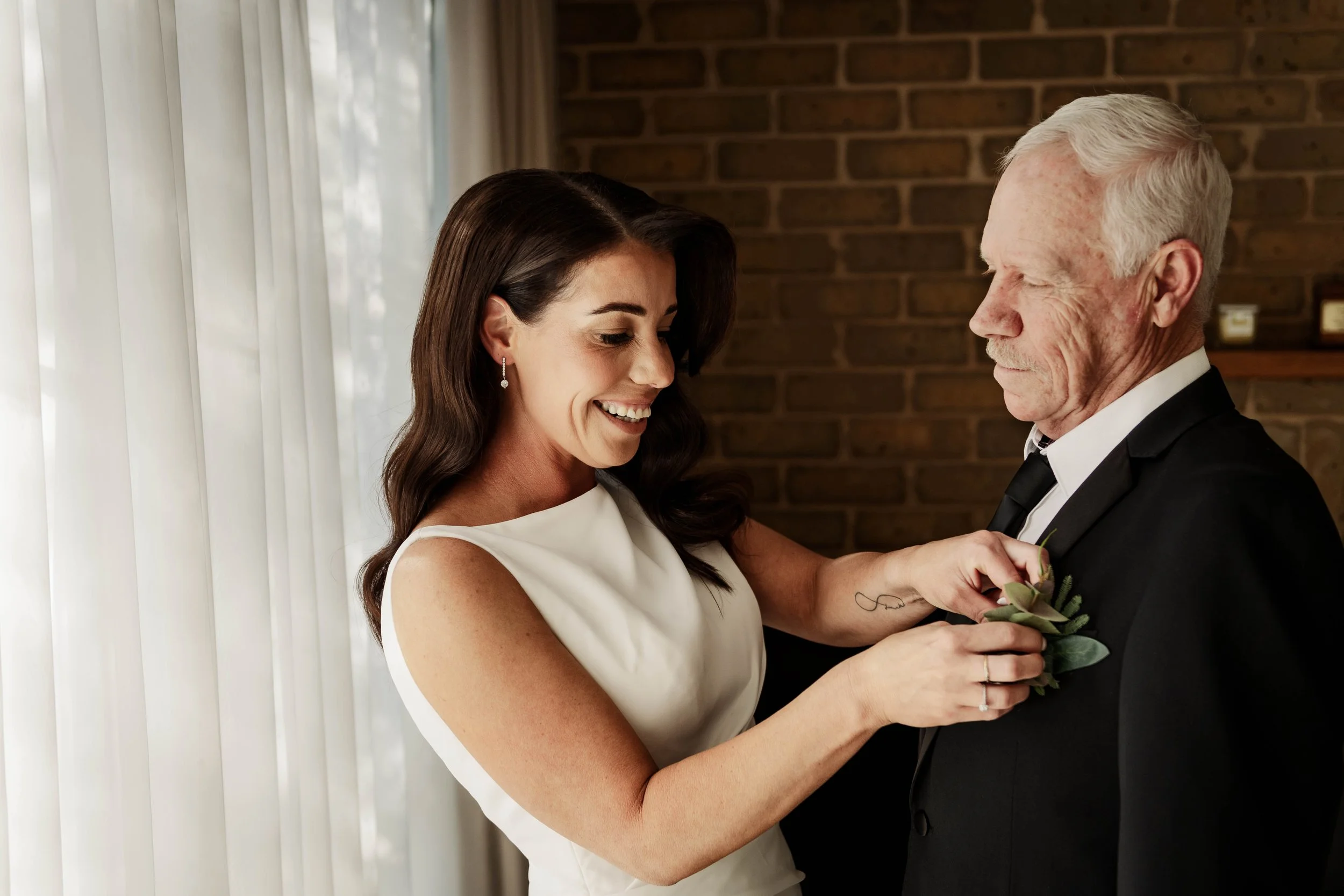 Bride pinning a boutonniere on her father's lapel while getting ready at Jason's Restaurant Beaconsfield Victoria