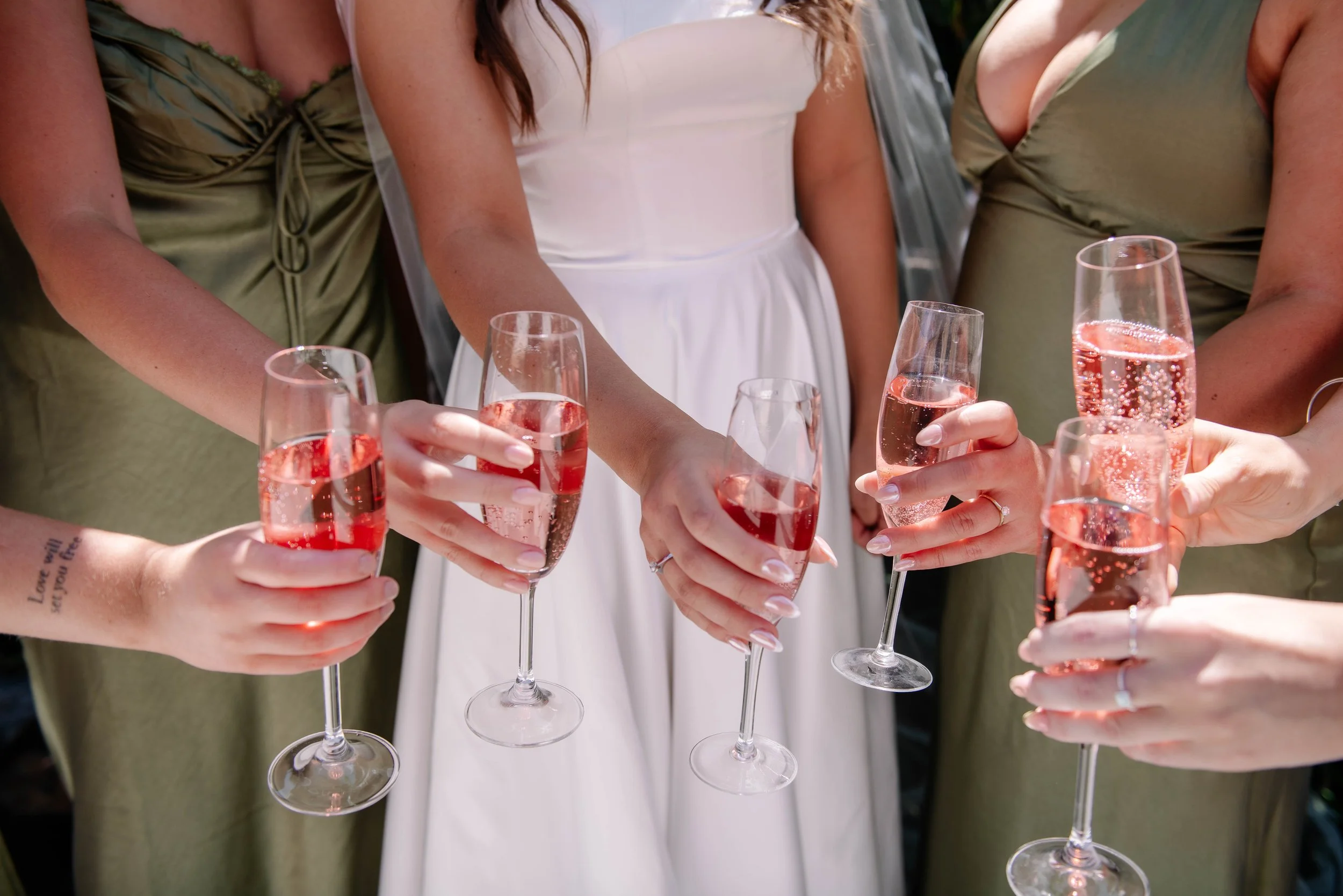 Close up of pink champagne glasses with bridesmaids before wedding