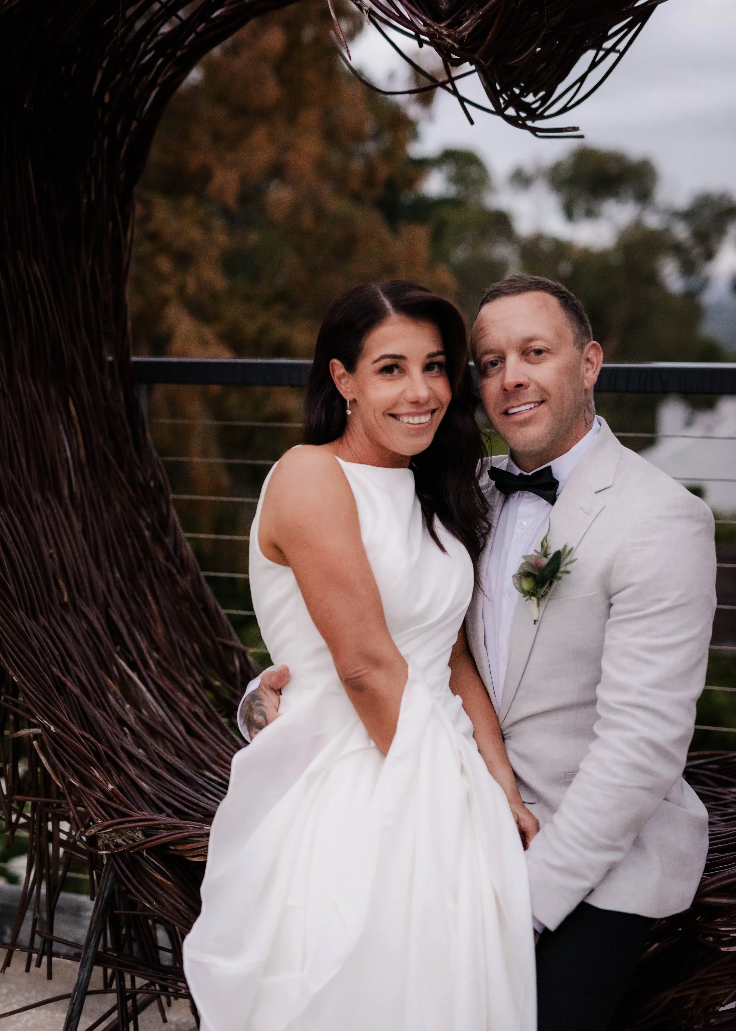 Bride and groom sitting together inside a rustic twig arch at Jason's Restaurant Beaconsfield wedding venue