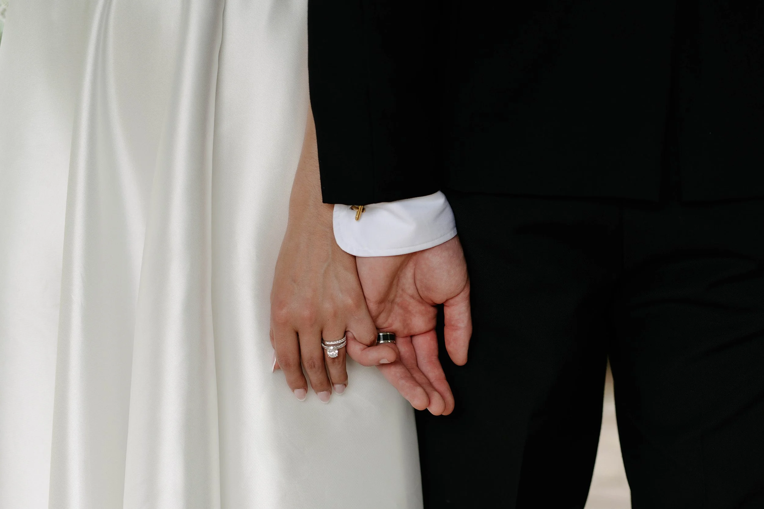 Close up of bride and groom holding hands showing diamond wedding ring and black groom's band at Daly Waters Rose Garden wedding Victoria