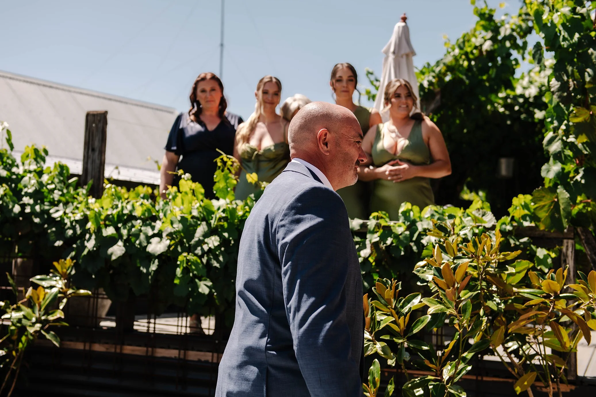 Brides father walks towards daughter in Ballarat garden with bridesmaids behind