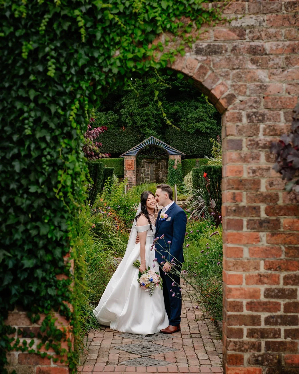 Cloudehill-Gardens-wedding-groom-kisses-bride-cheek-archway.jpg