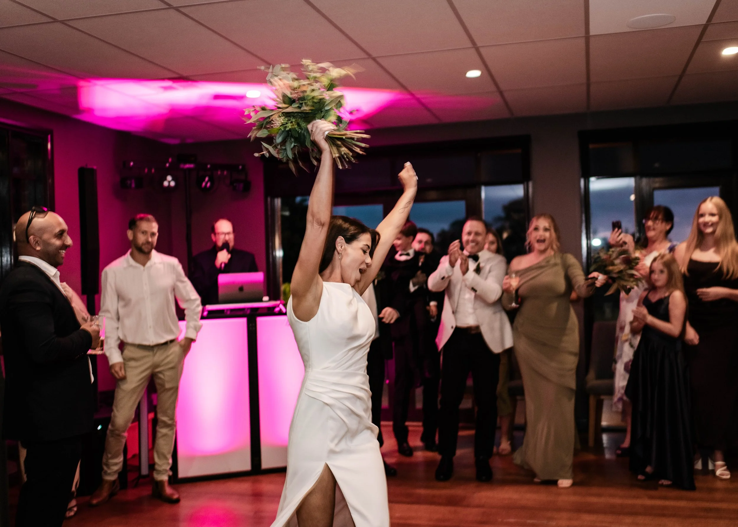 Bride raising bouquet before the toss on the dance floor at Jason's Restaurant Beaconsfield wedding reception
