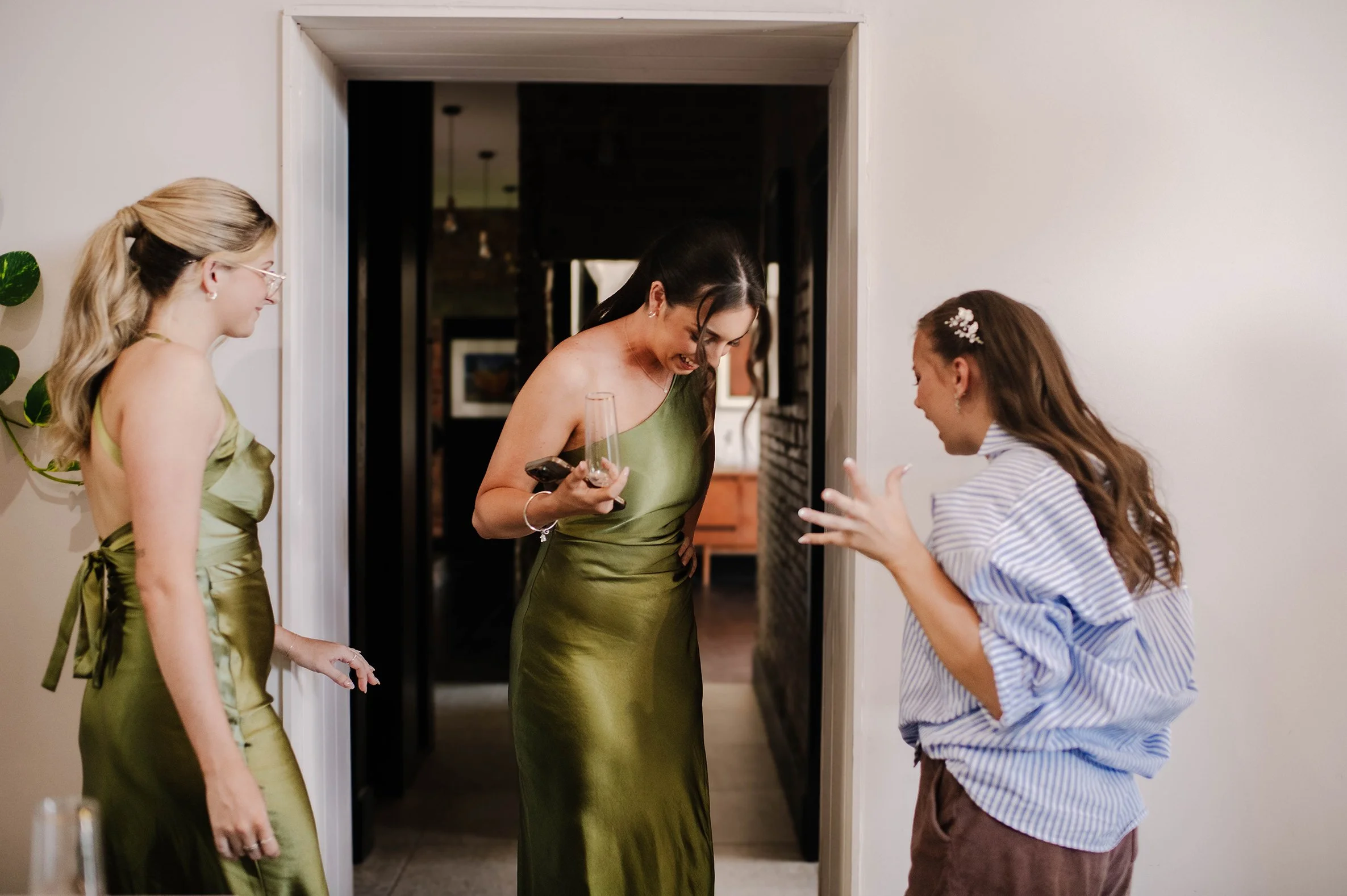 Bride expresses amazement with hands out at bridesmaids green dress
