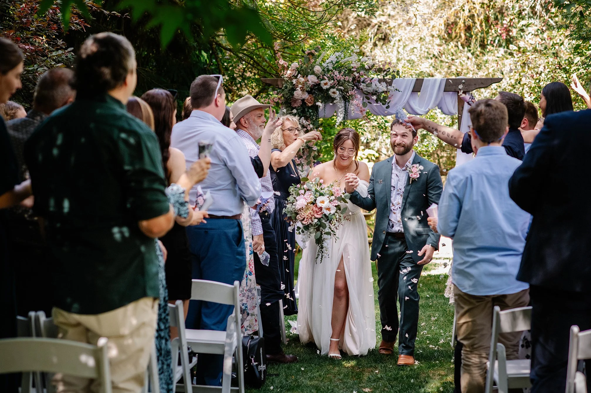 Groom hoorays at petal exit down aisle from arbor at Chateau Dore Bendigo