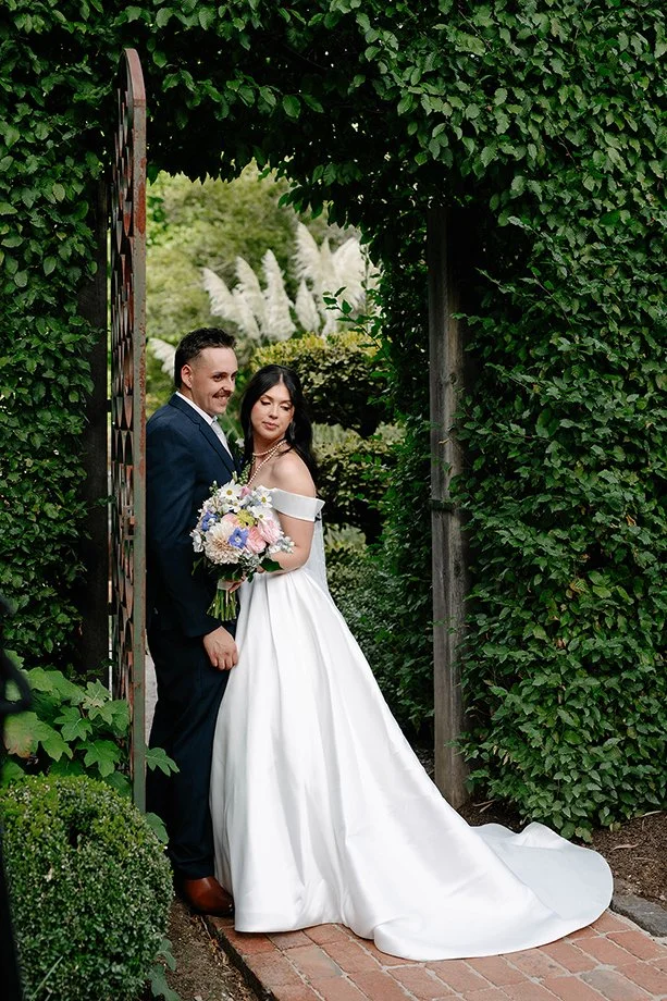 Bride and groom posing in a vine-covered garden archway at Cloudehill Gardens Dandenong Ranges wedding venue