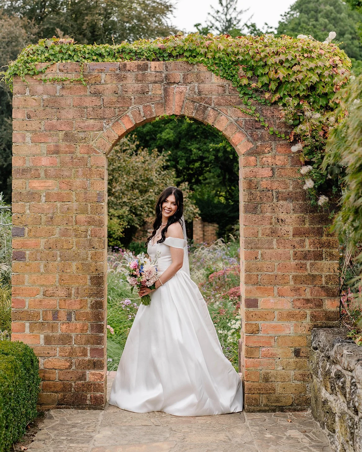 Bride smiling in a heritage brick archway covered in ivy at Cloudehill Gardens Dandenong Ranges wedding venue