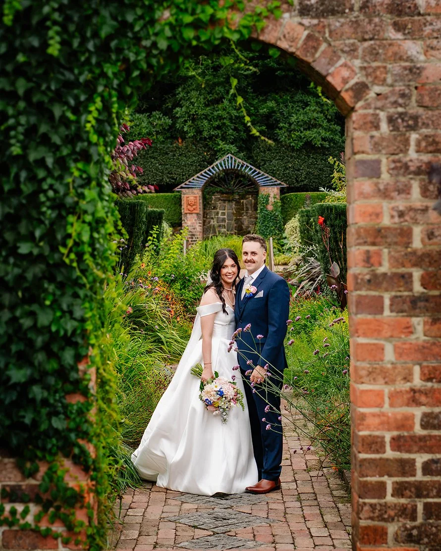 couple look at camera through archway covered in ivy at Cloudehill Gardens and smile cheek to cheek