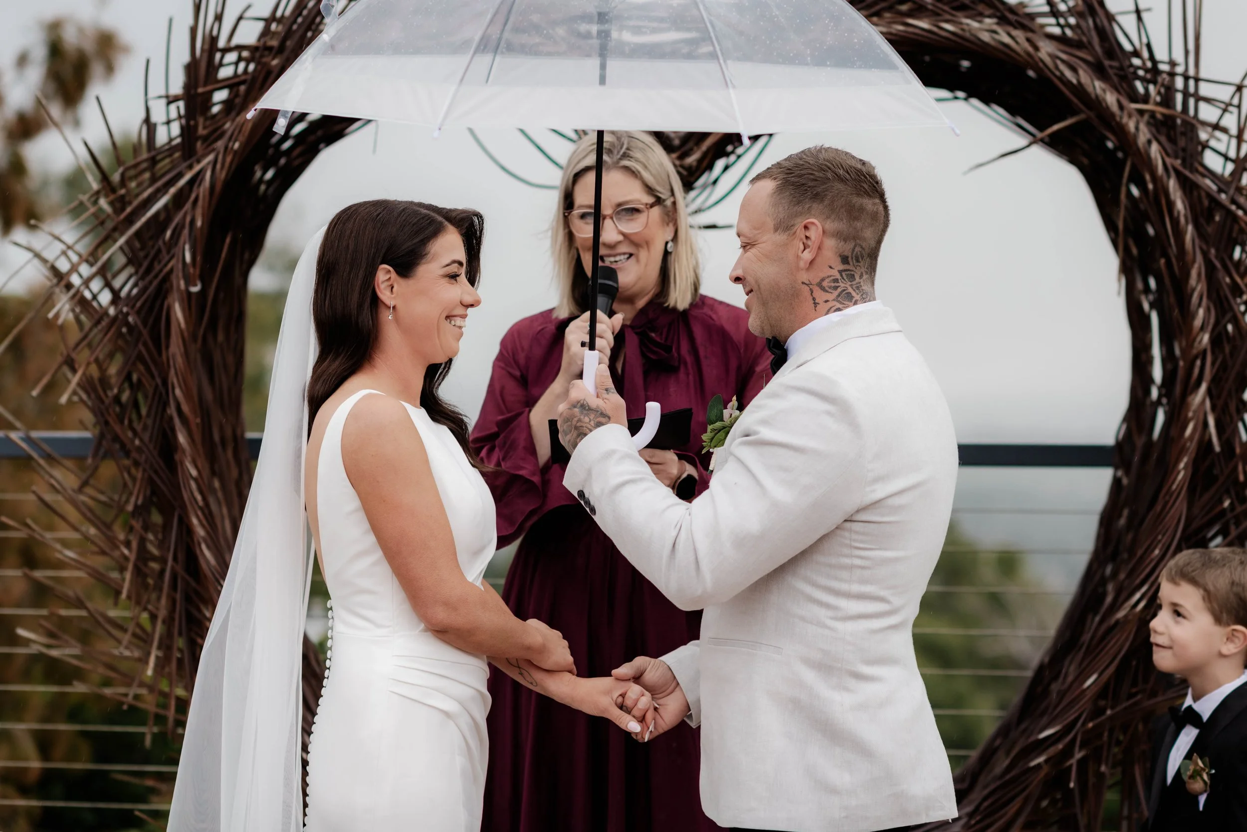Bride and groom exchanging vows under a rustic twig arch with celebrant and child attendant at Jason's Restaurant Beaconsfield