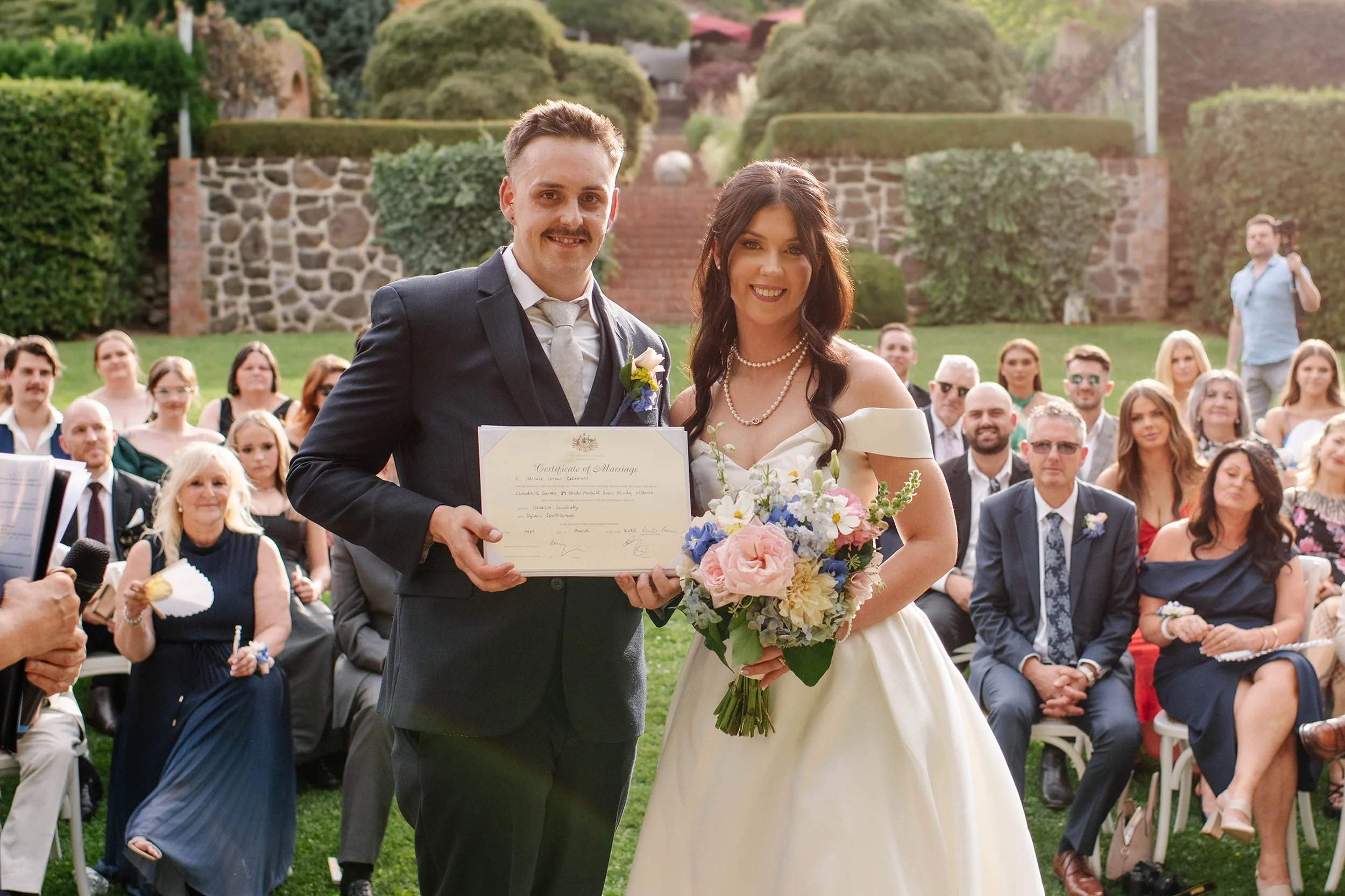 bride-groom-hold-certificate-guests-behind-olinda.jpg