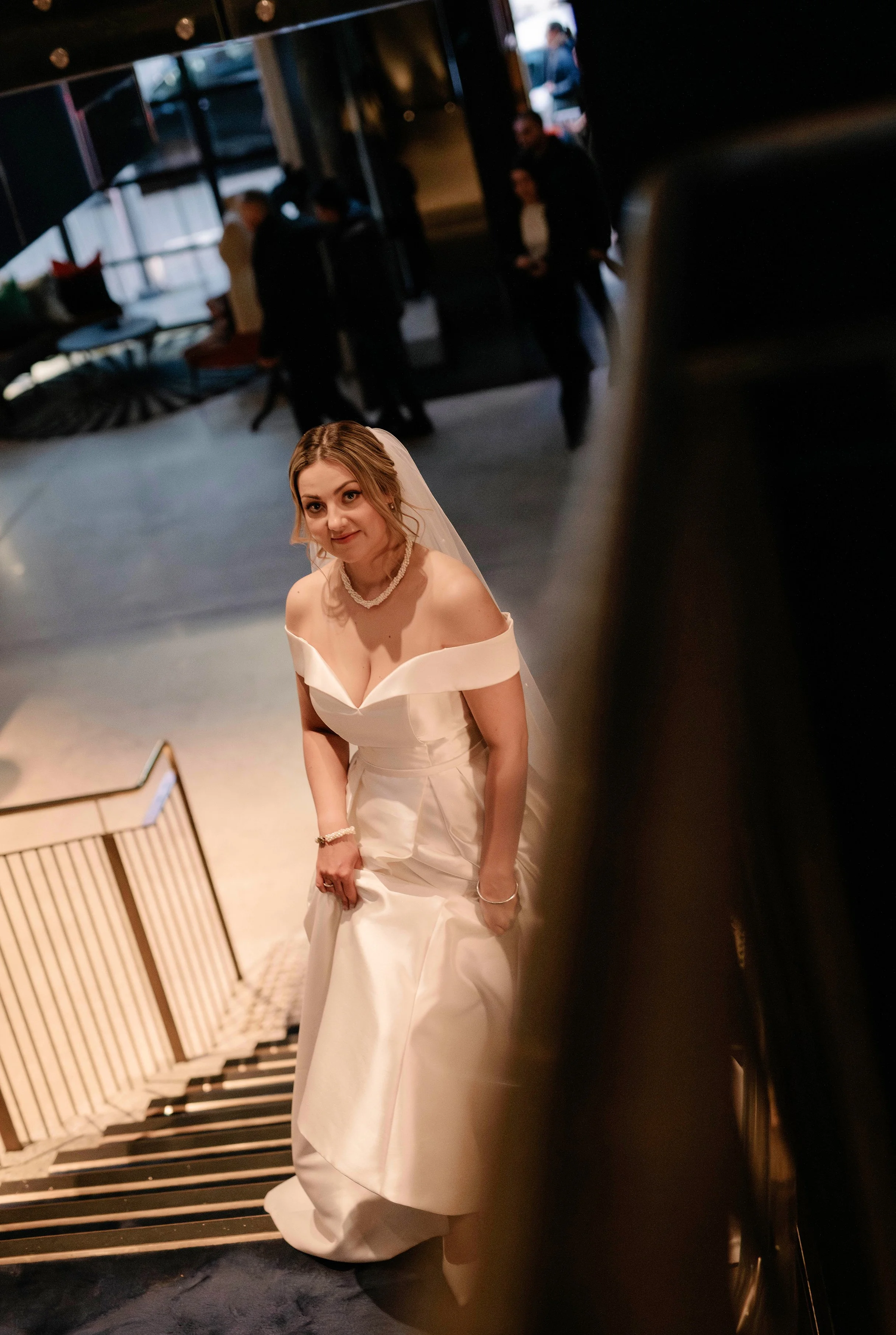 bride peeking around the corner at the camera as she walks up the stairs of QT Hotel in Melbourne