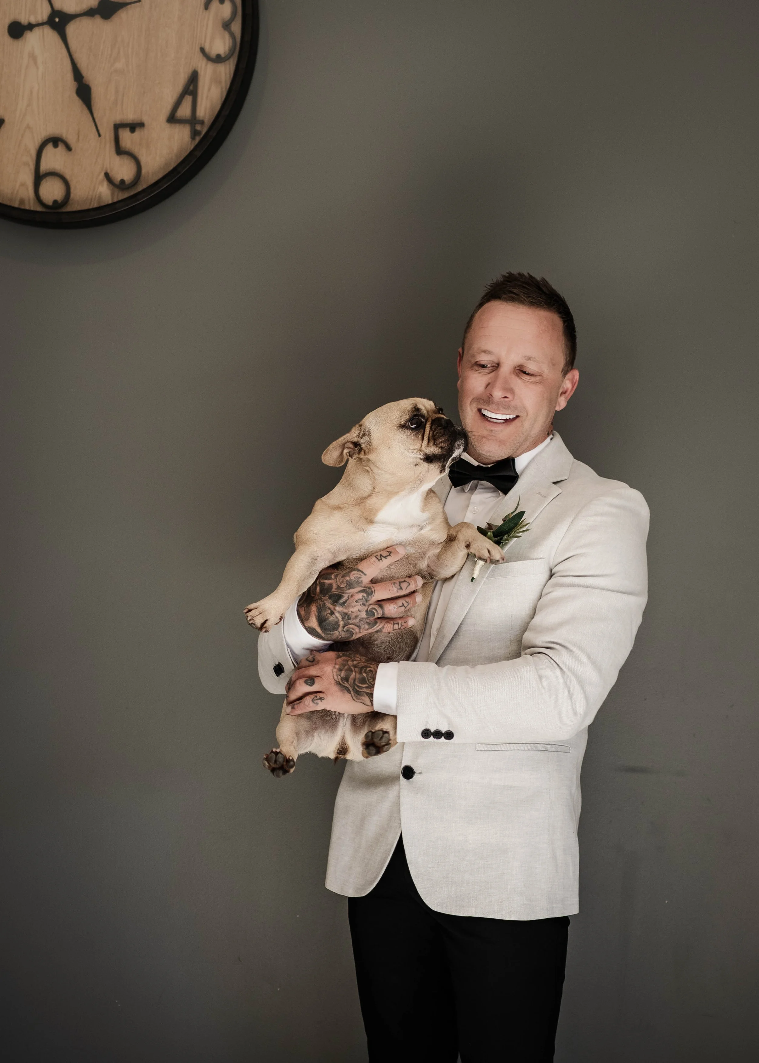 Groom in white jacket holding a French bulldog while getting ready at Jason's Restaurant Beaconsfield Victoria