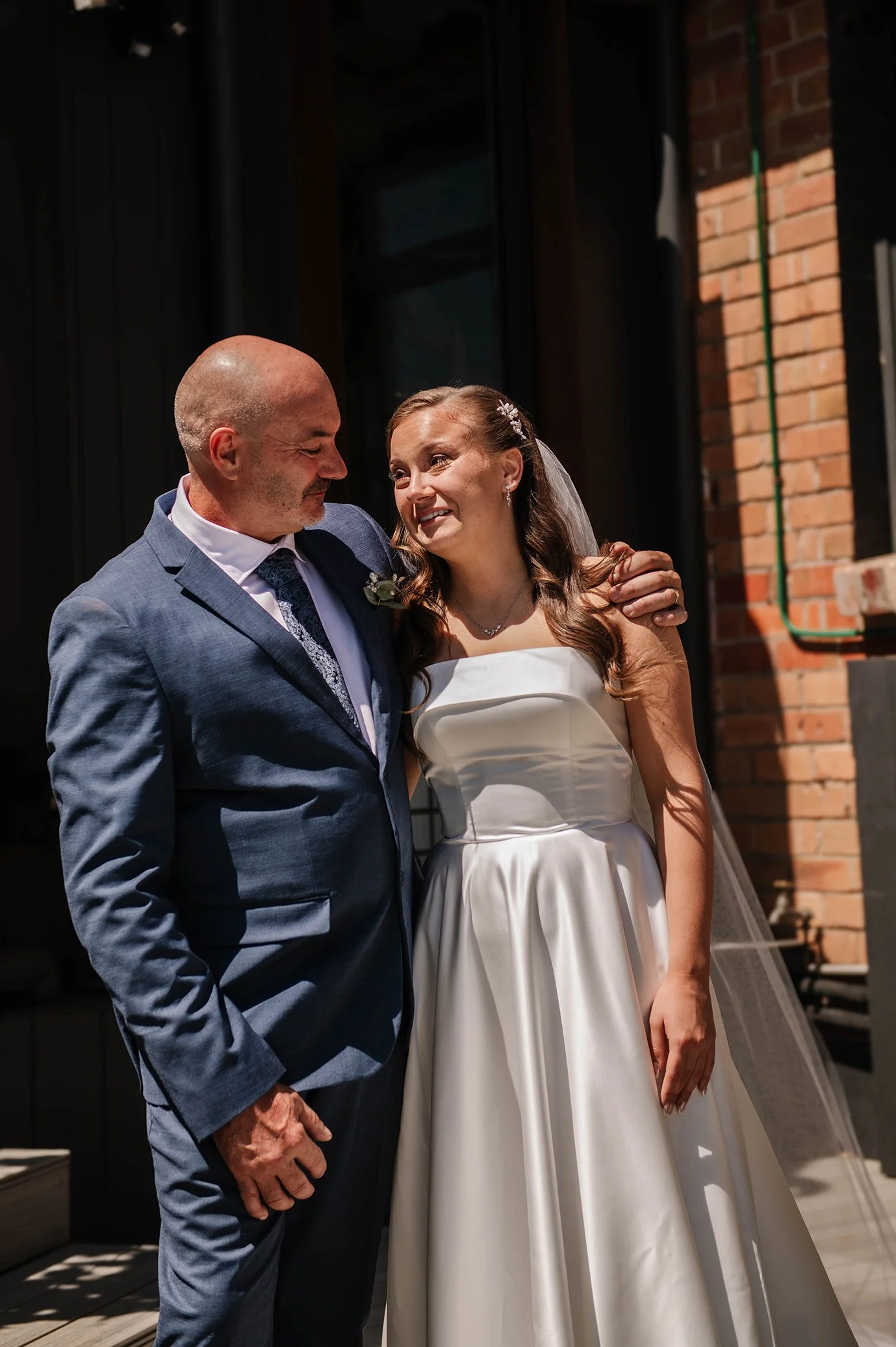 Father of bride with arm around his daughter smiling at Ballarat house