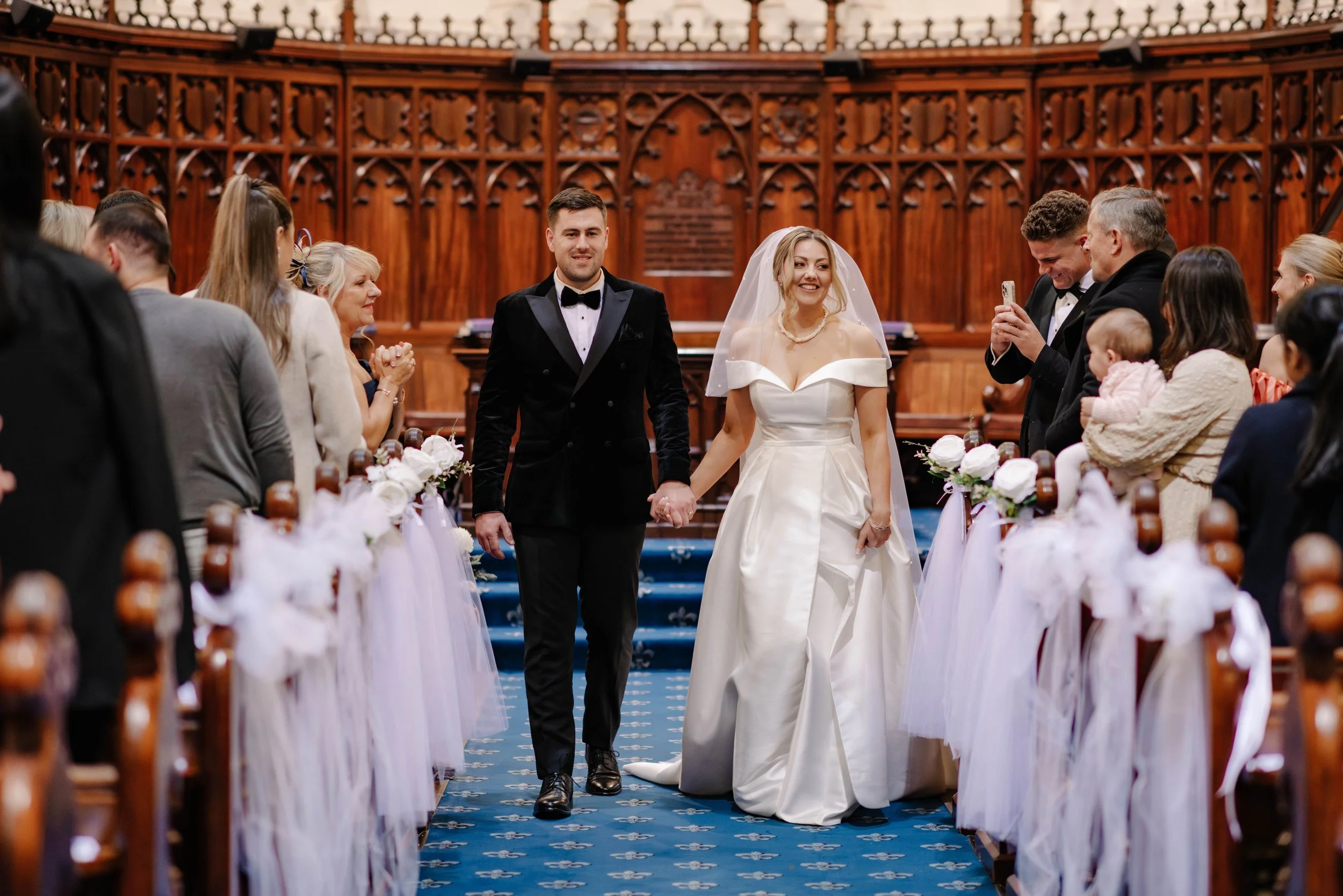 bride and groom exit down the aisle smiling as the guests clap