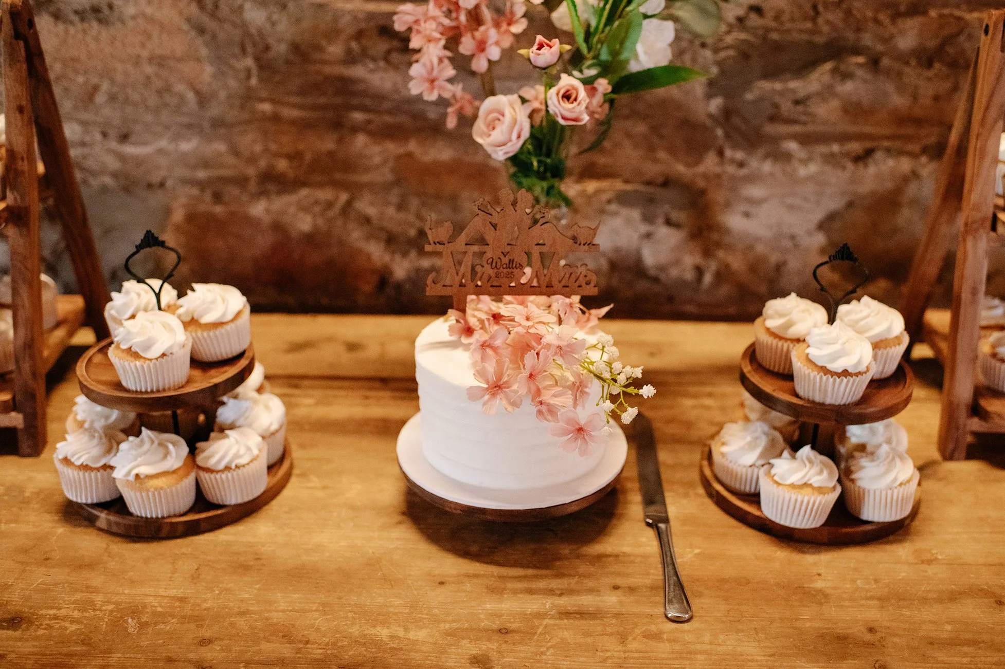 wedding cake surrounded by cupcakes in pink and white at wedding reception in Bendigo