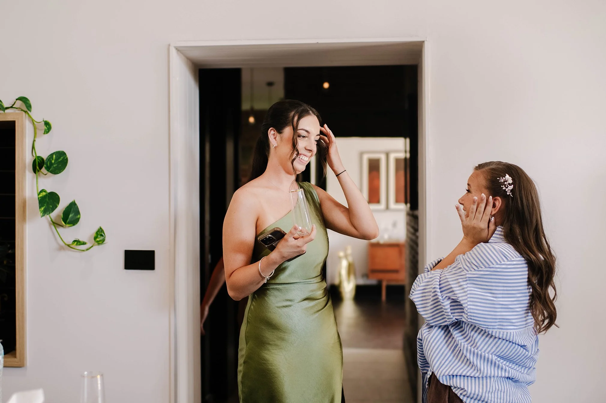 Bride clasps face in hands as bridesmaid comes out in first look
