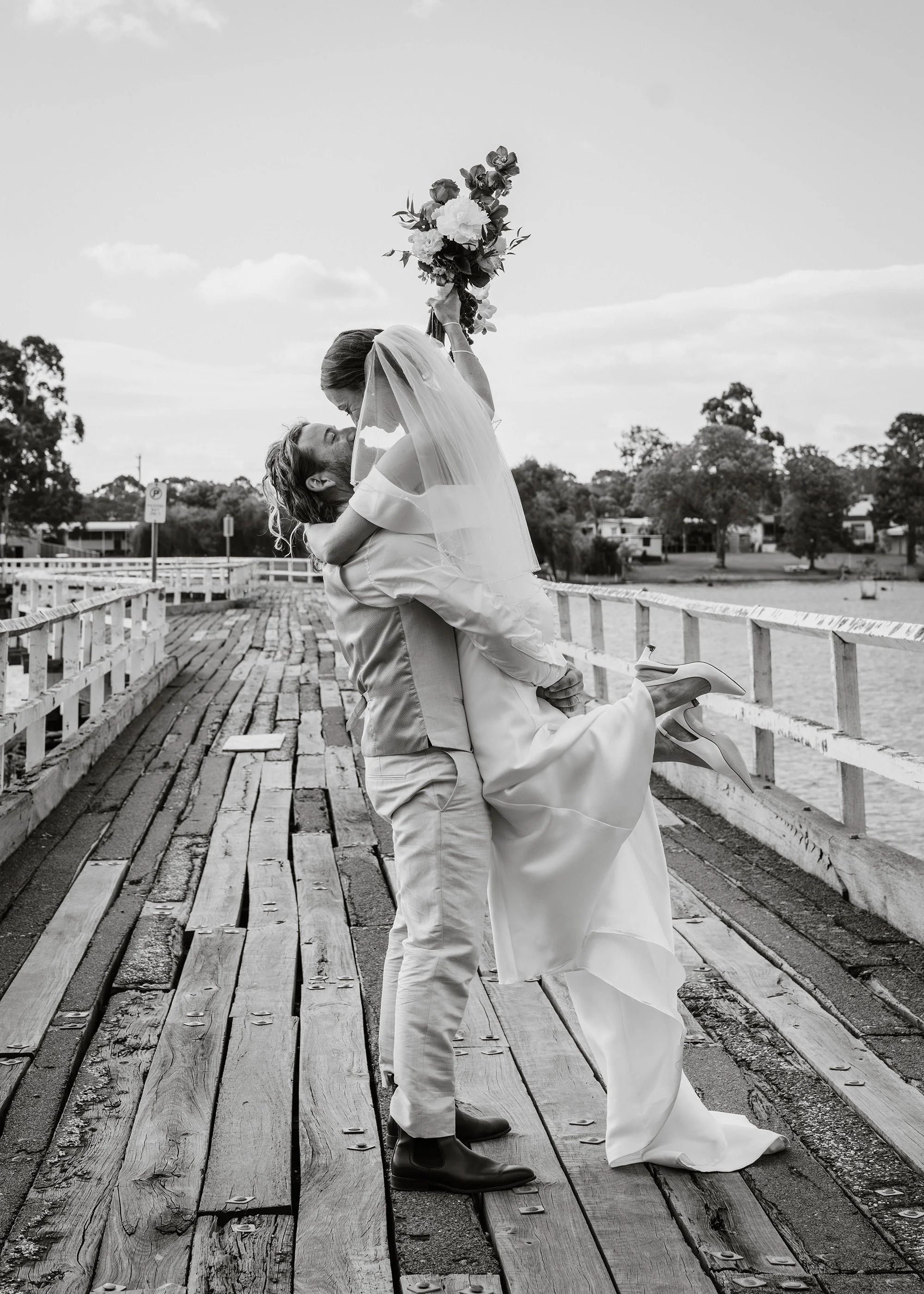 Bride and groom sharing a kiss on a rustic timber jetty at The Boathouse Nagambie wedding venue