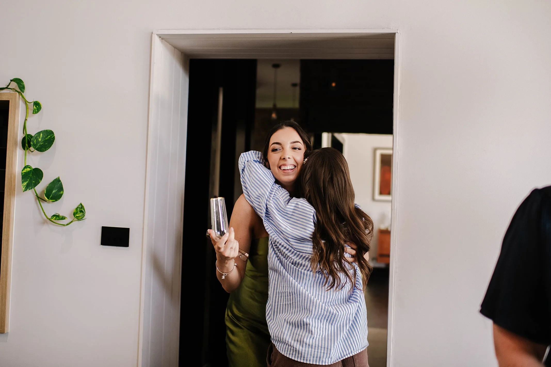 Bride hugs bridesmaid around the neck warmly as bridesmaid smiles