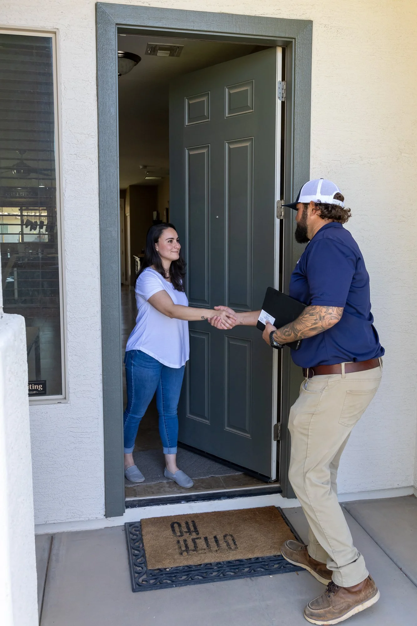 Varsity termite and pest technician shaking hands with homeowner