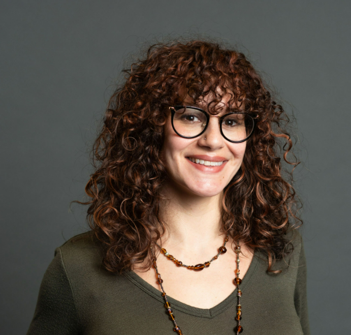 Carrington Talent Group client Paula Young smiles warmly at the camera. She's wearing a brown beaded necklace and a olive green long sleeve t-shirt.