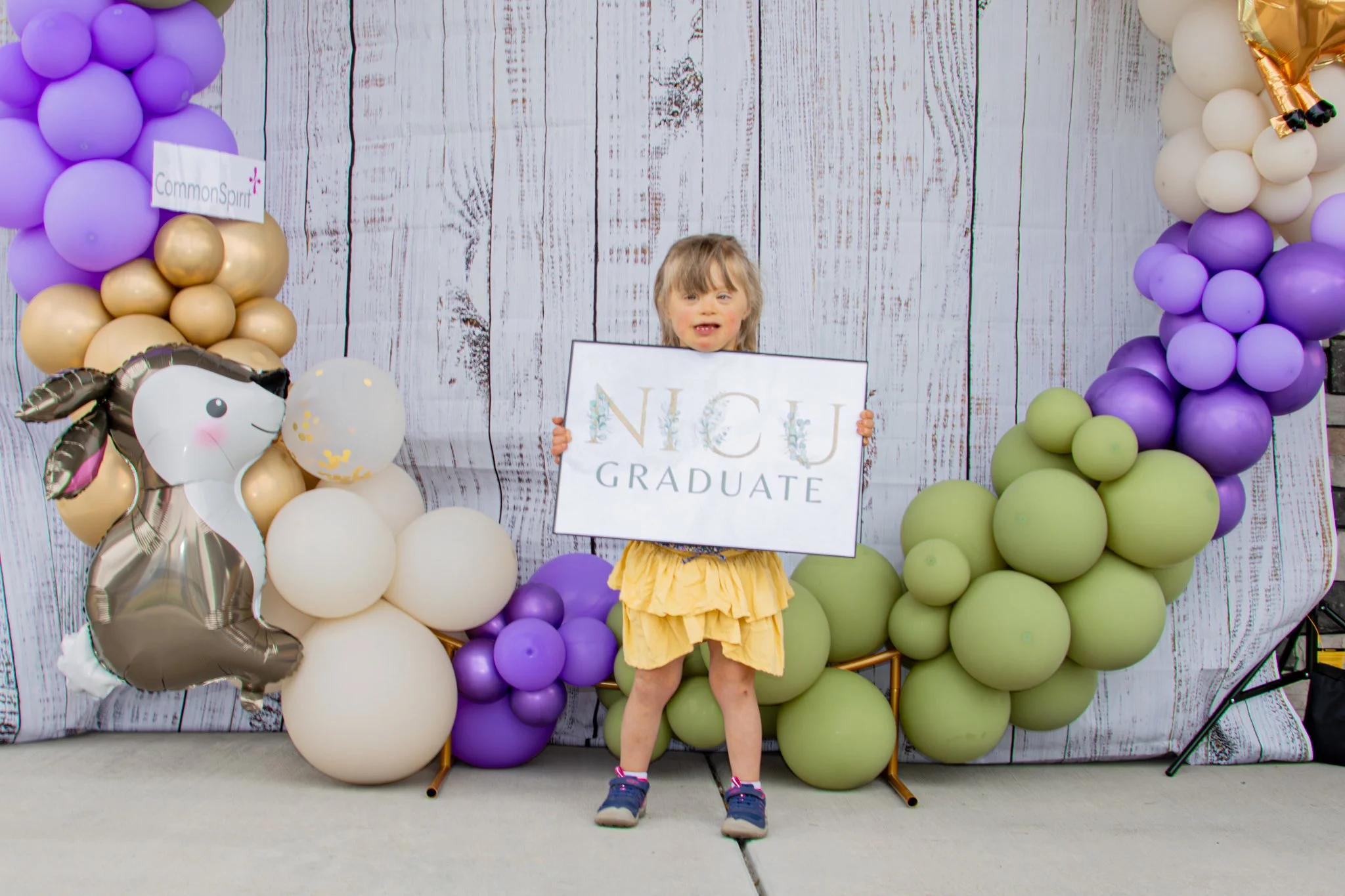 young girl holding a NICU graduate sign