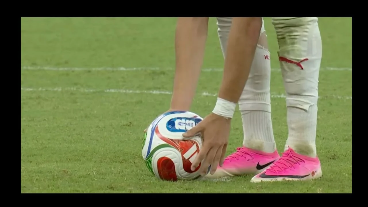 A footballer positioning the ball ahead of taking a penalty kick