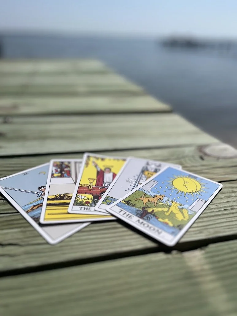 tarot cards near the water laying on a wooden pier