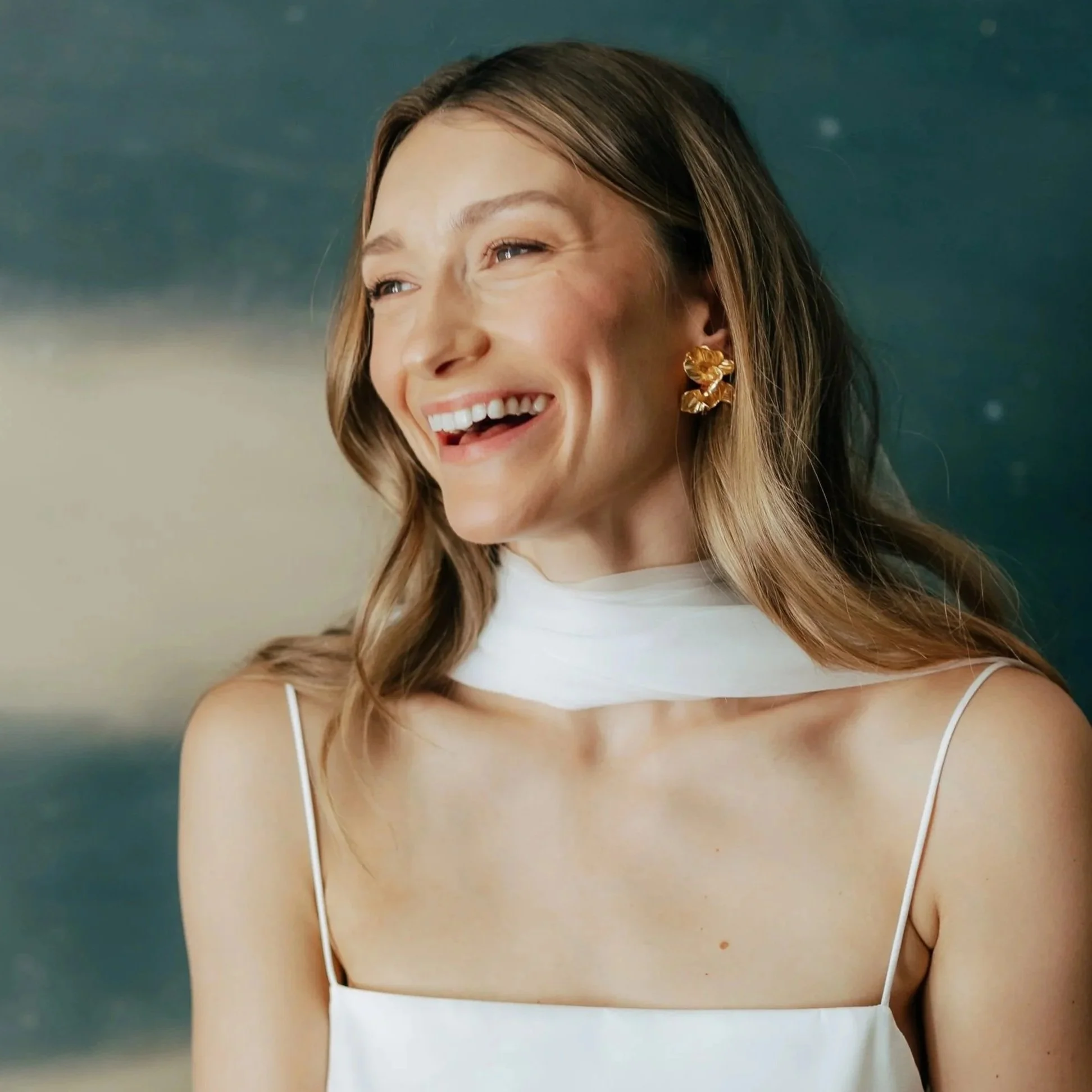 A bride with blonde hair wearing a white wedding dress and veil, smiling.