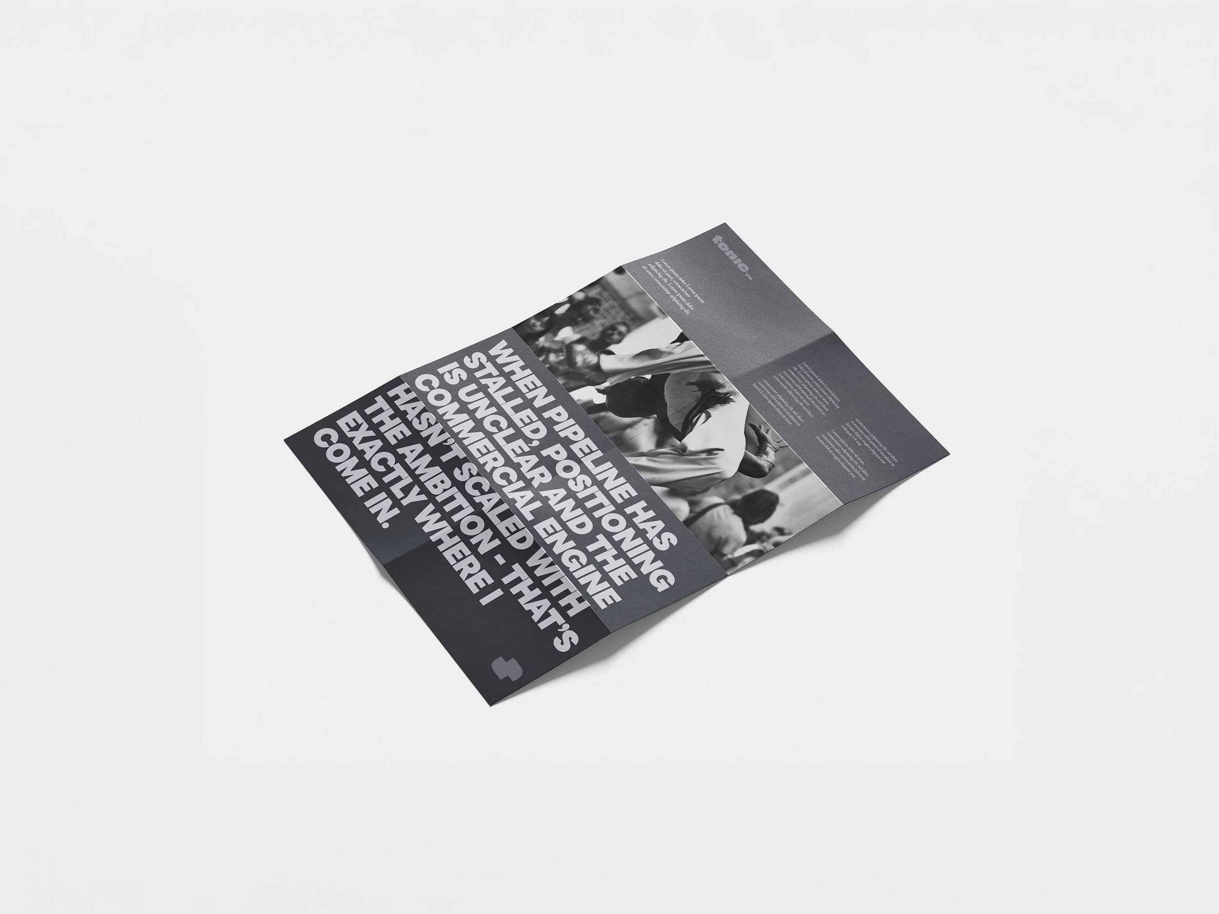A black and white folded brochure or flyer with bold large text on the front and text and images on the inside, lying on a white surface.